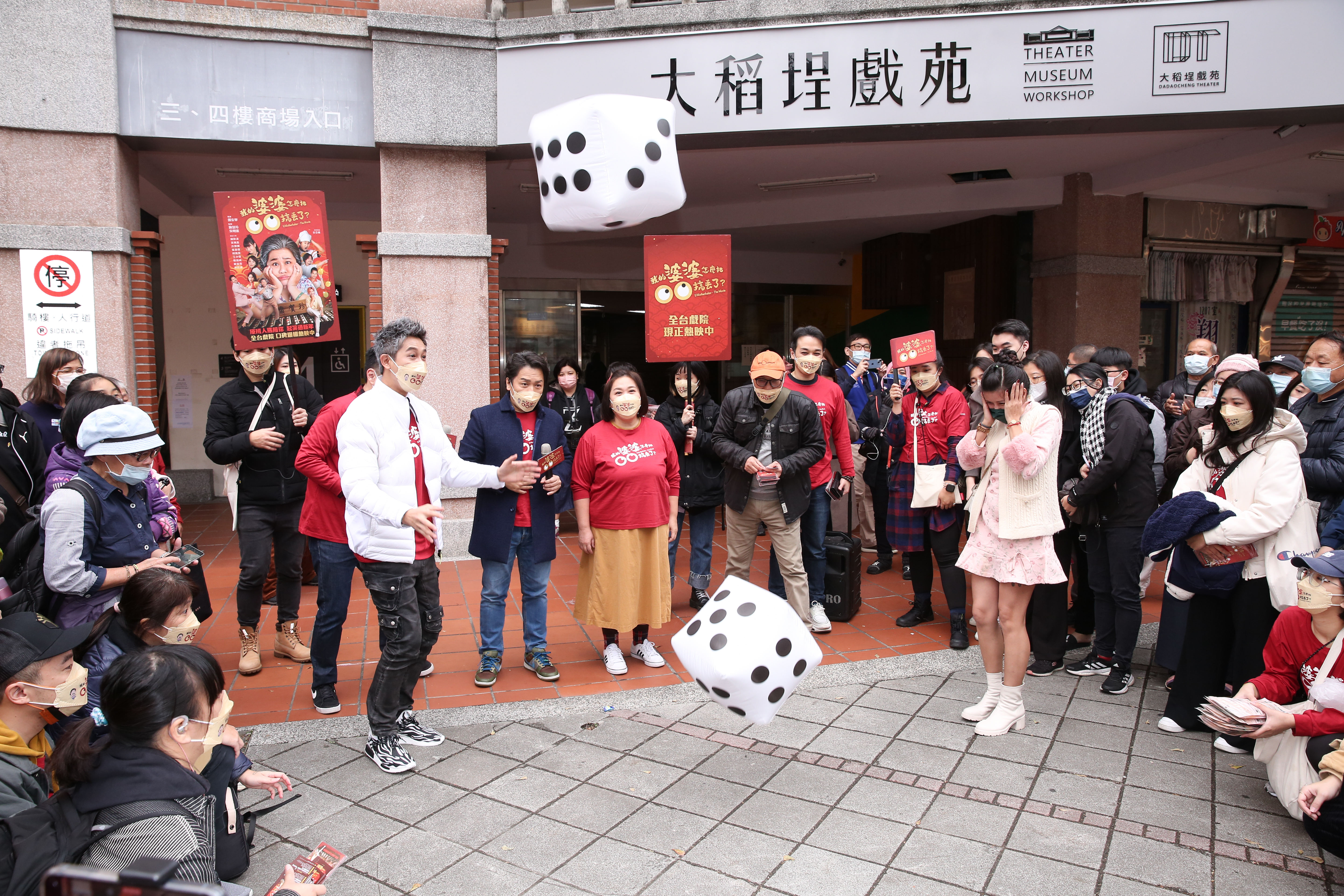 眾人在廣場與遊客玩擲骰子遊戲，一群人玩得十分開心。