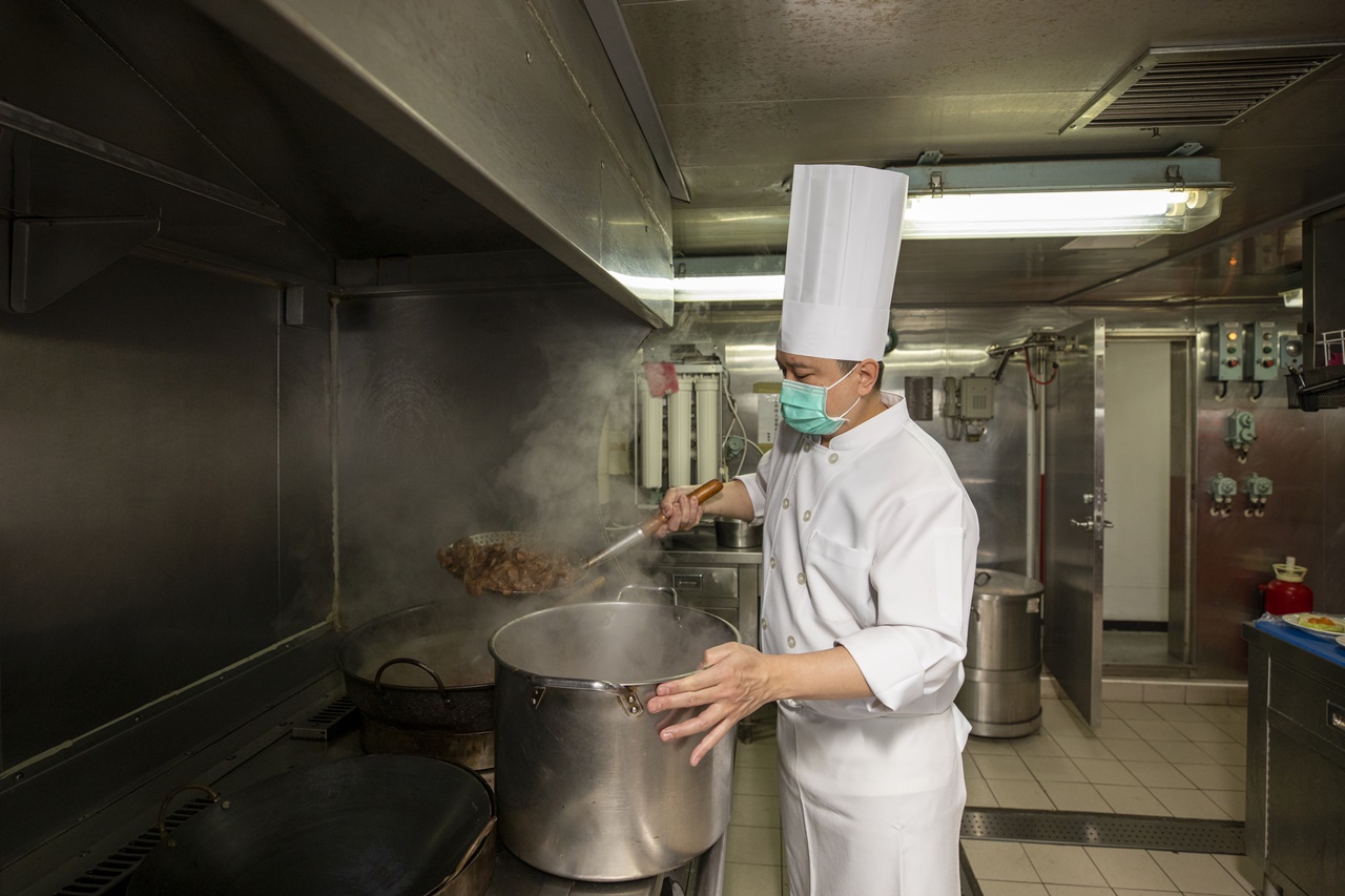巡護七號大廚莊健宏拿著大型鍋鏟，翻炒著香氣撲鼻的牛肉。