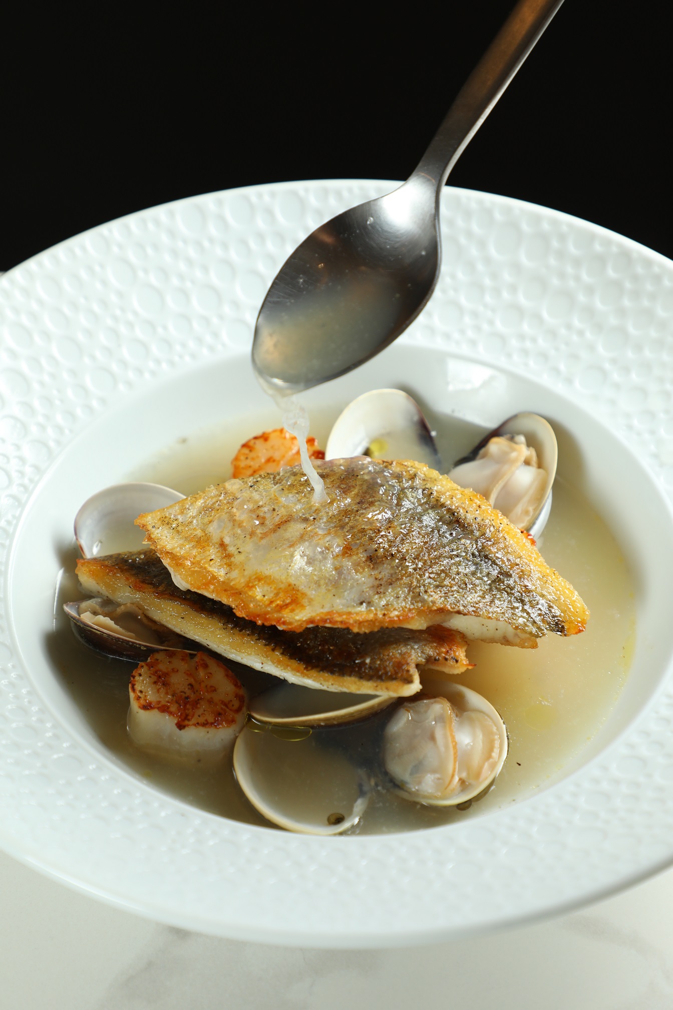 「季節鮮魚」以乳清加入魚湯，與干貝、蛤蠣共呈鮮美。（780元／份）