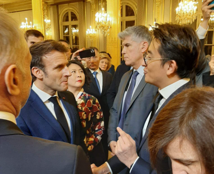 巴黎律師公會登錄律師詹文睿（右，戴眼鏡者）出席活動，法國總統馬克宏（左）和他親切握手。（翻攝自Nicolas Chan臉書）