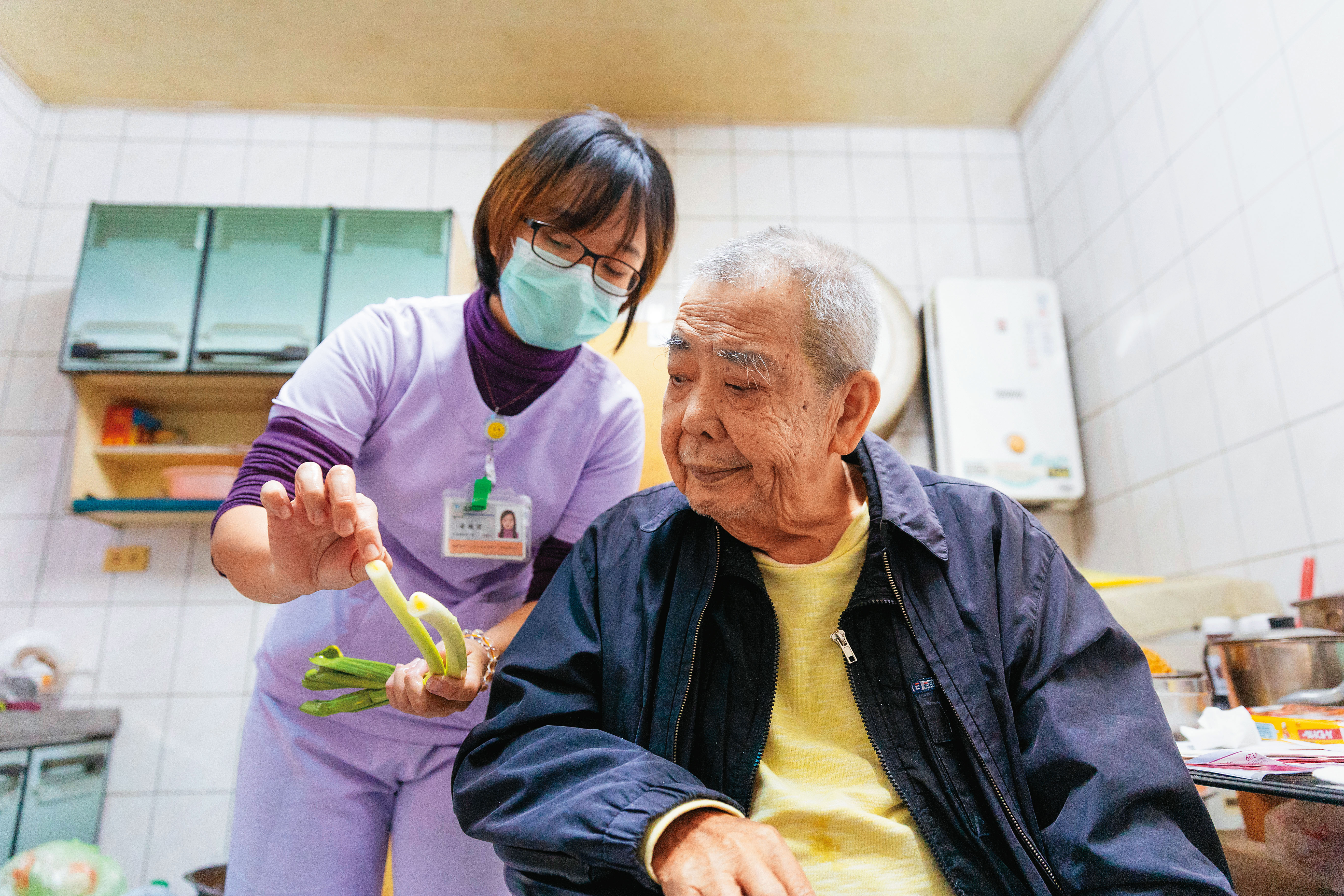 黃曉君（左）一來，就加入廚房一起幫忙，但她似乎不太擅長料理，問王南（右）蒜苗怎麼下刀比較好？