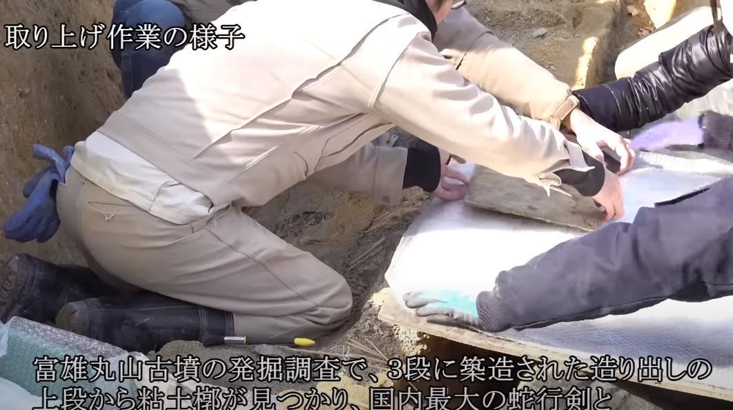 日本考古團隊在富雄丸山古墳發現兩件國寶級古物,考古人員小心翼翼移動古物。(翻攝Youtube頻道「奈良市動画チャンネル」)