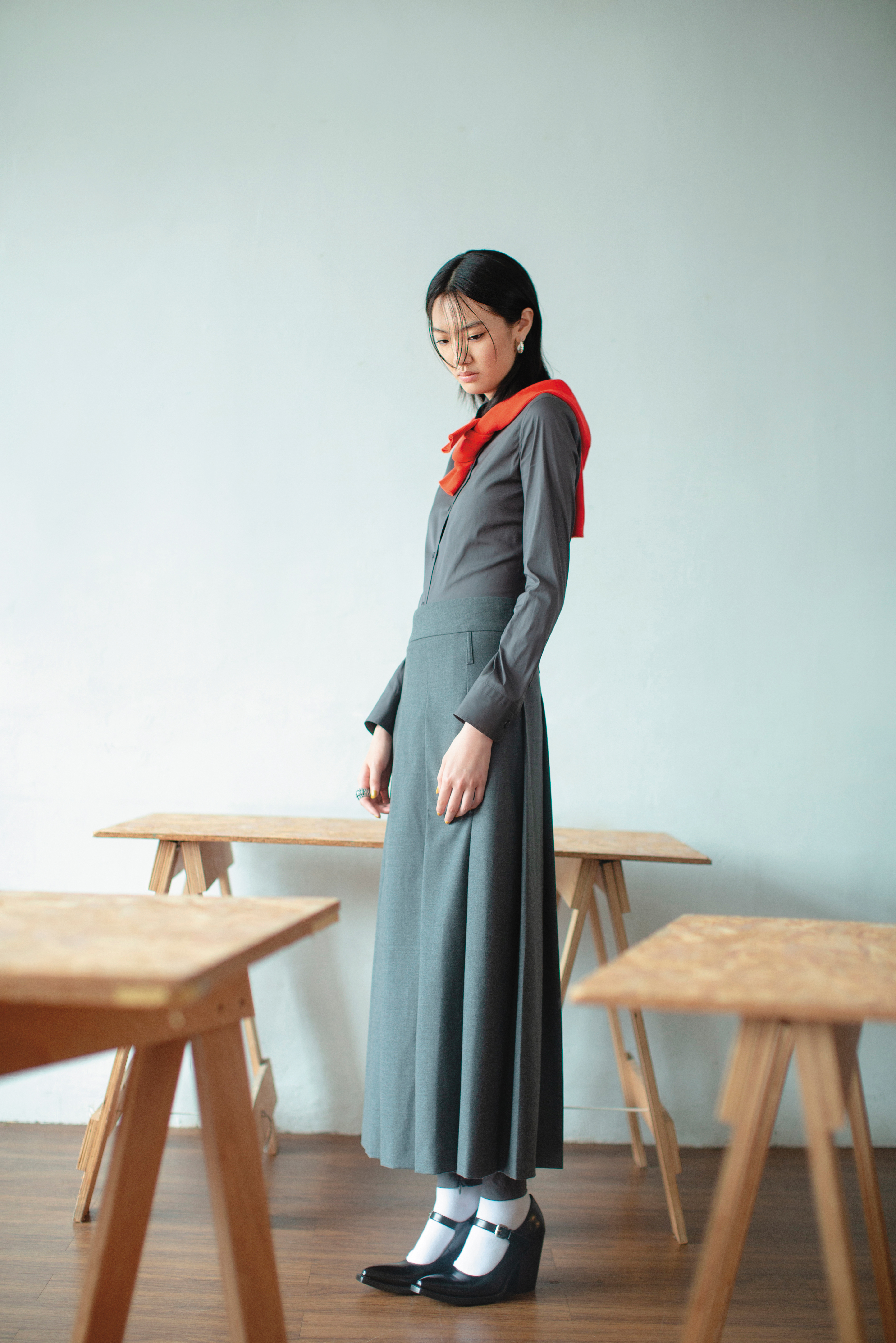 灰色連身褲 價格店洽 by PRADA／紅色針織衫 價格店洽 by PRADA／灰色百褶長裙 NT$47,800 by SPORTMAX／黑色繫帶瑪莉珍高跟鞋 價格店洽 by PRADA／Matrix耳環 NT$6,350 by SWAROVSKI／Hyperbola個性戒指 NT$14,000 by SWAROVSKI