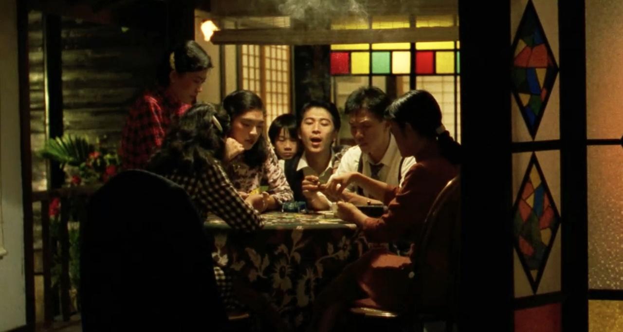 她不說就真的很難認。《悲情城市》唐綺陽(左三托腮者)飾演酒家女打四色牌,和演員高捷、太保等人同框。(牽猴子提供)
