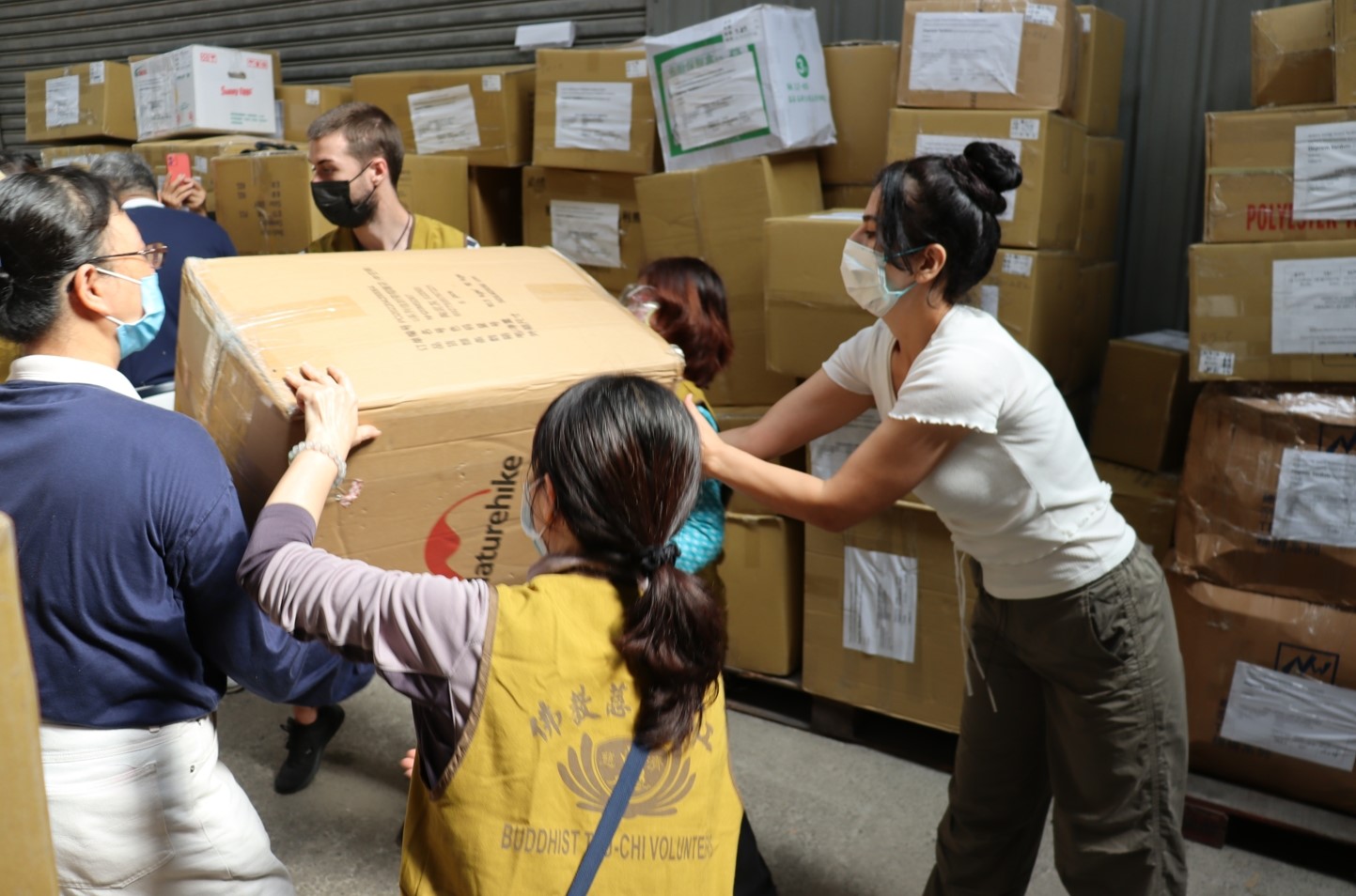 土耳其辦事處代表貝定可的夫人（右）也與慈濟志工一起投入搬運物資。（慈濟基金會提供）