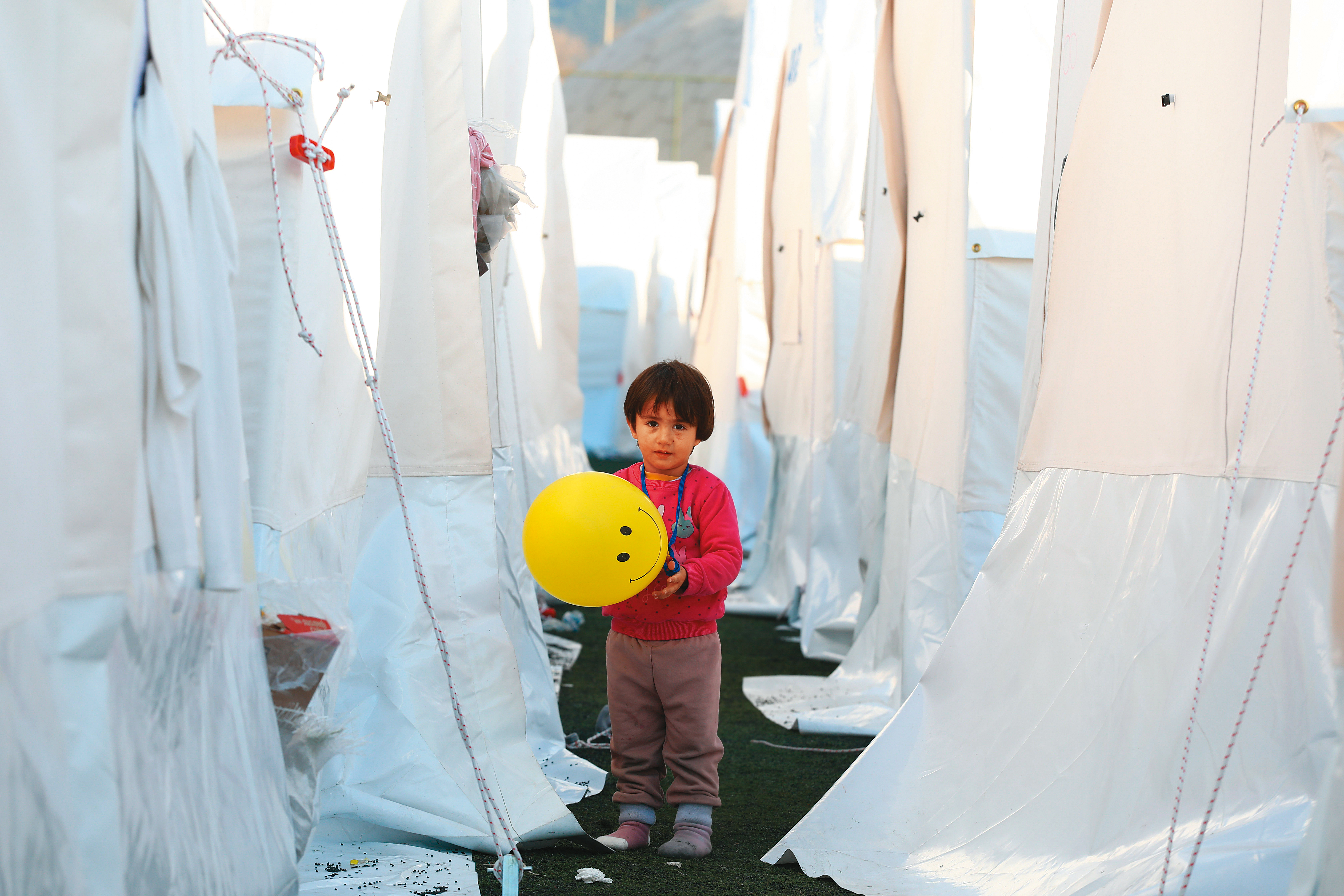紅衣男童持黃色氣球穿梭玩樂，與白色帳篷形成強烈對比。