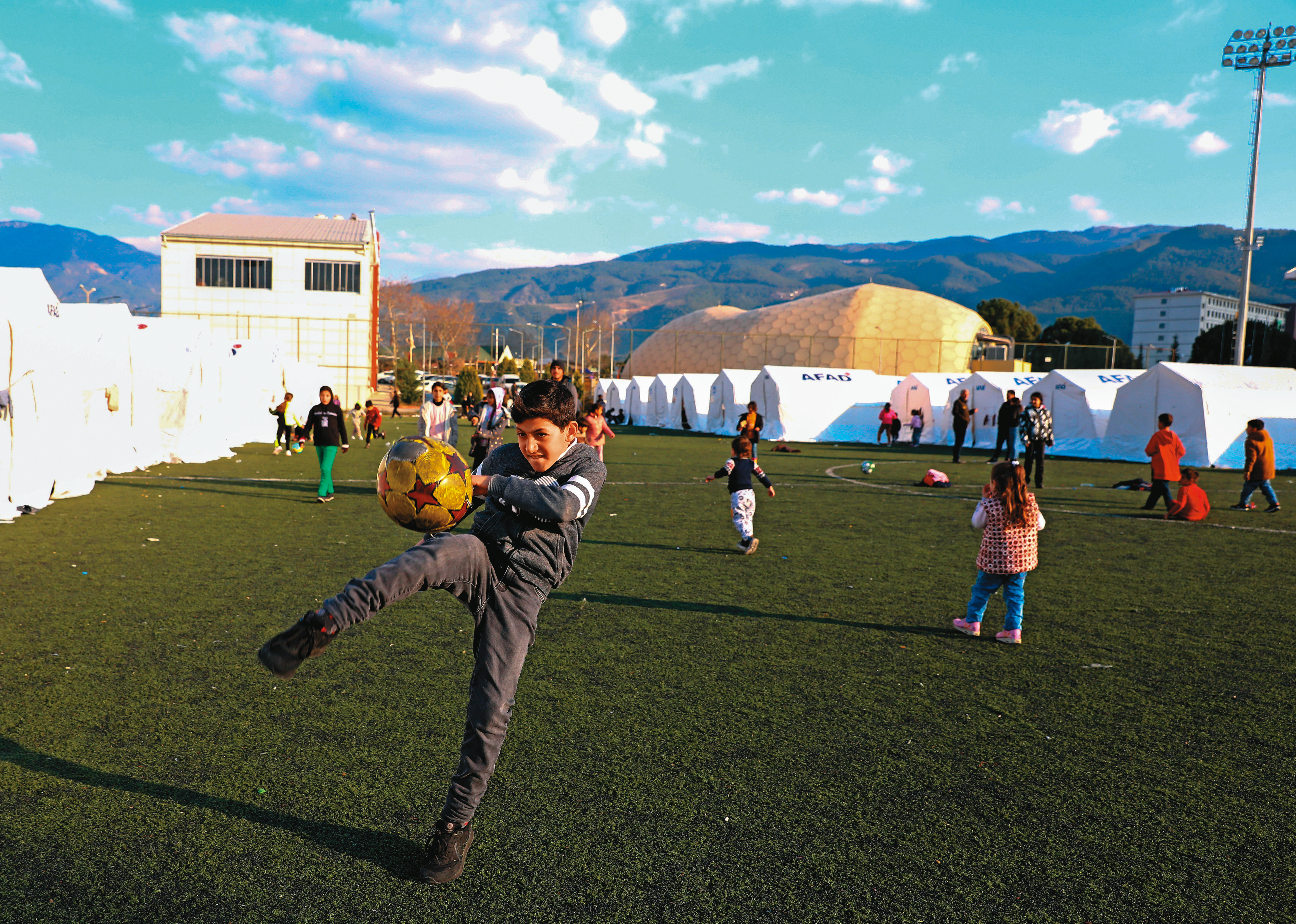 倖存孩童們在收容所綠地上踢球玩樂，他們的笑容，正是土耳其期盼的未來。