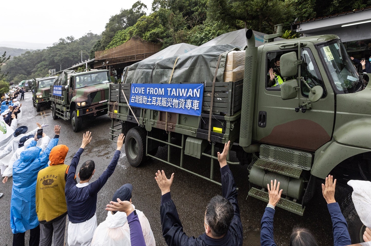 志工及民眾向國軍載運土耳其賑災物資車隊揮手致意。(慈濟基金會提供)