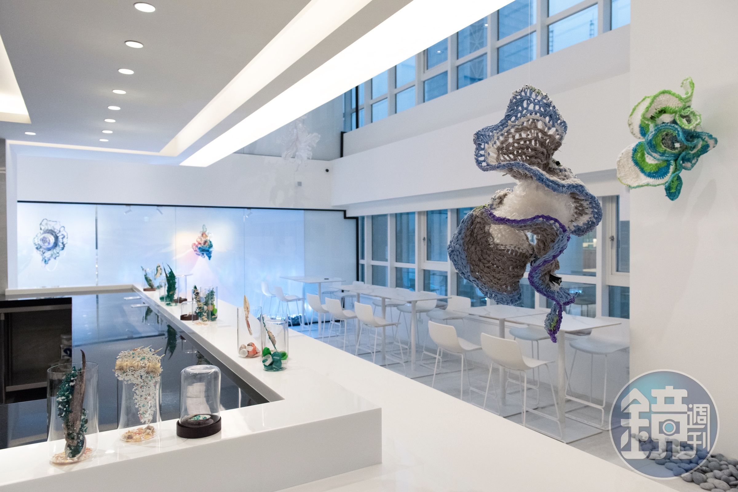 「The Seedin Lab」在純白空間裝飾藝術家洪郁雯以舊衣物、塑膠袋、寶特瓶等材料，編織出型態如花瓣的裝置藝術品。（The Seedin Lab提供）
