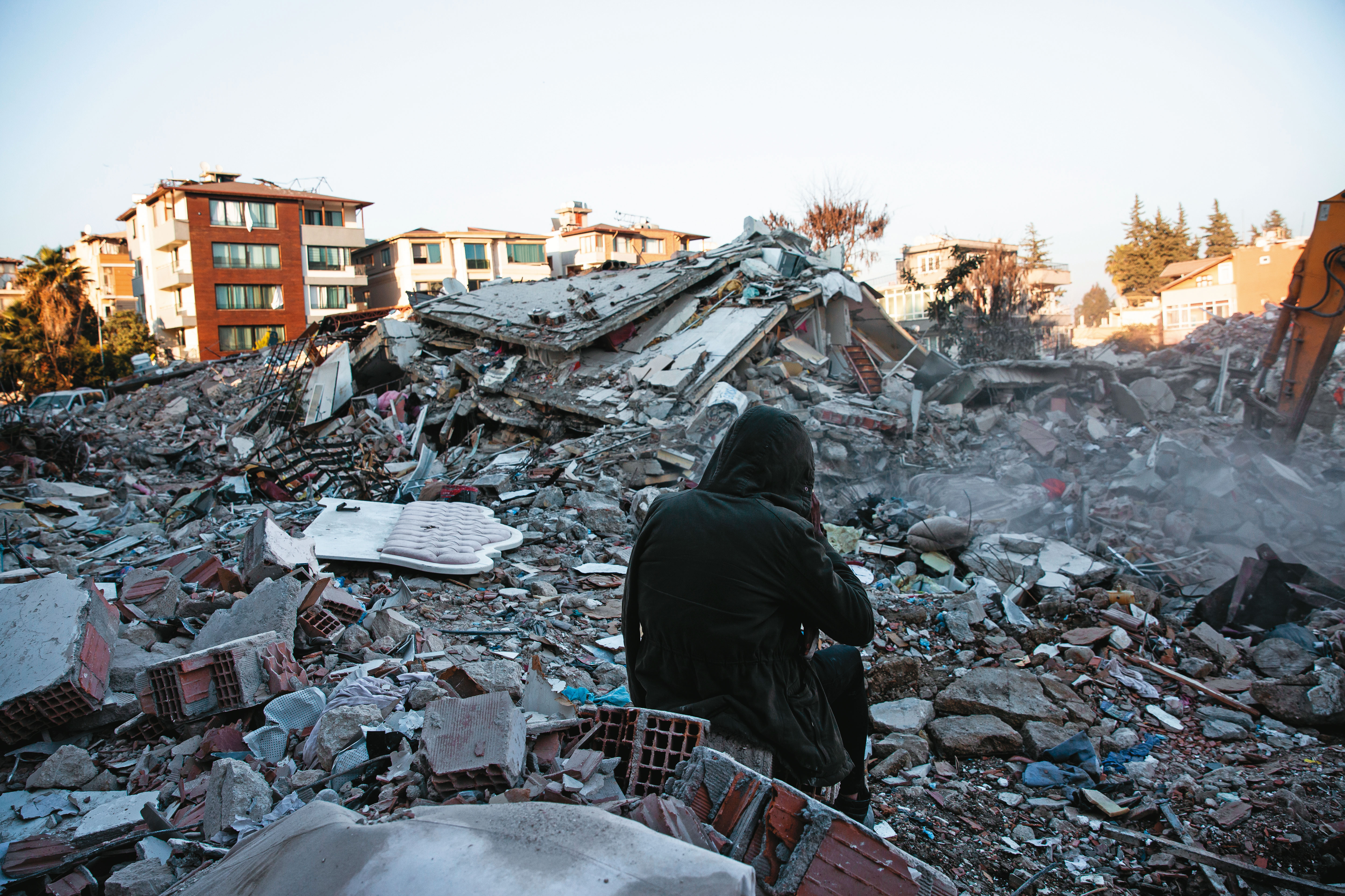 面對滿目瘡痍的家園，土耳其災民只能靜靜坐在開挖的怪手前。（鄒保祥攝）