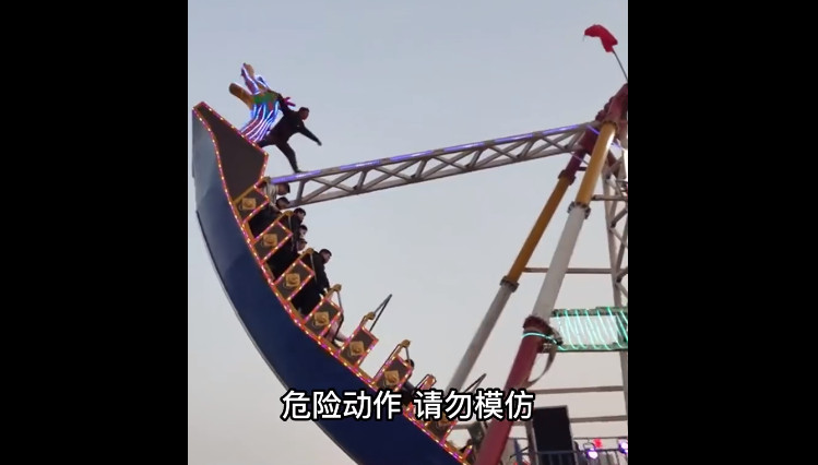 一名男遊客在中國山西一座遊樂園搭乘海盜船，沒想到在遊客設施擺動時竟在無防護措施下站到船頭。（翻攝微博@新聞晨報）