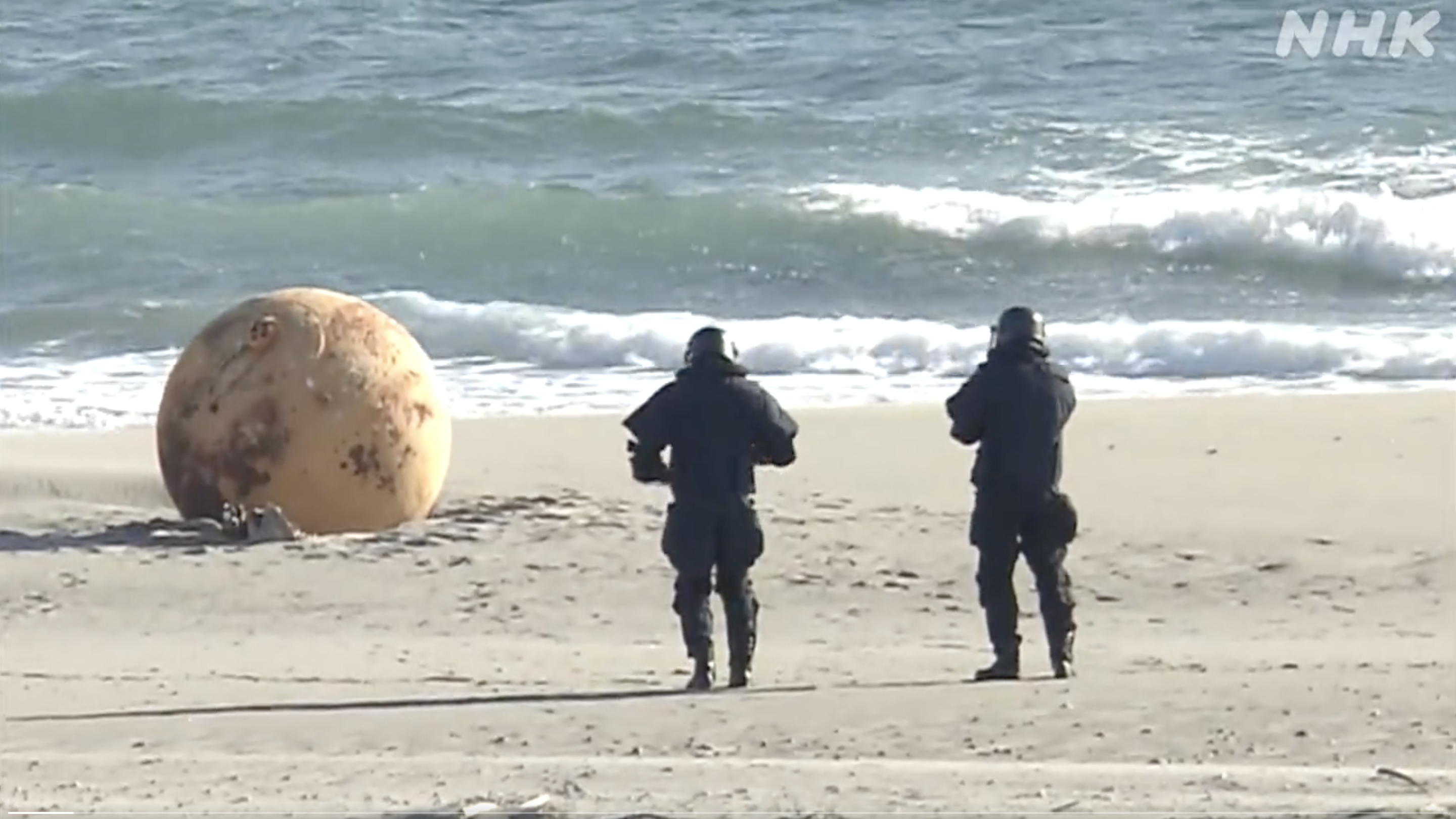 日本海岸出現神祕巨球，警方出動爆裂物小組封鎖處理。（翻攝自NHK推特）