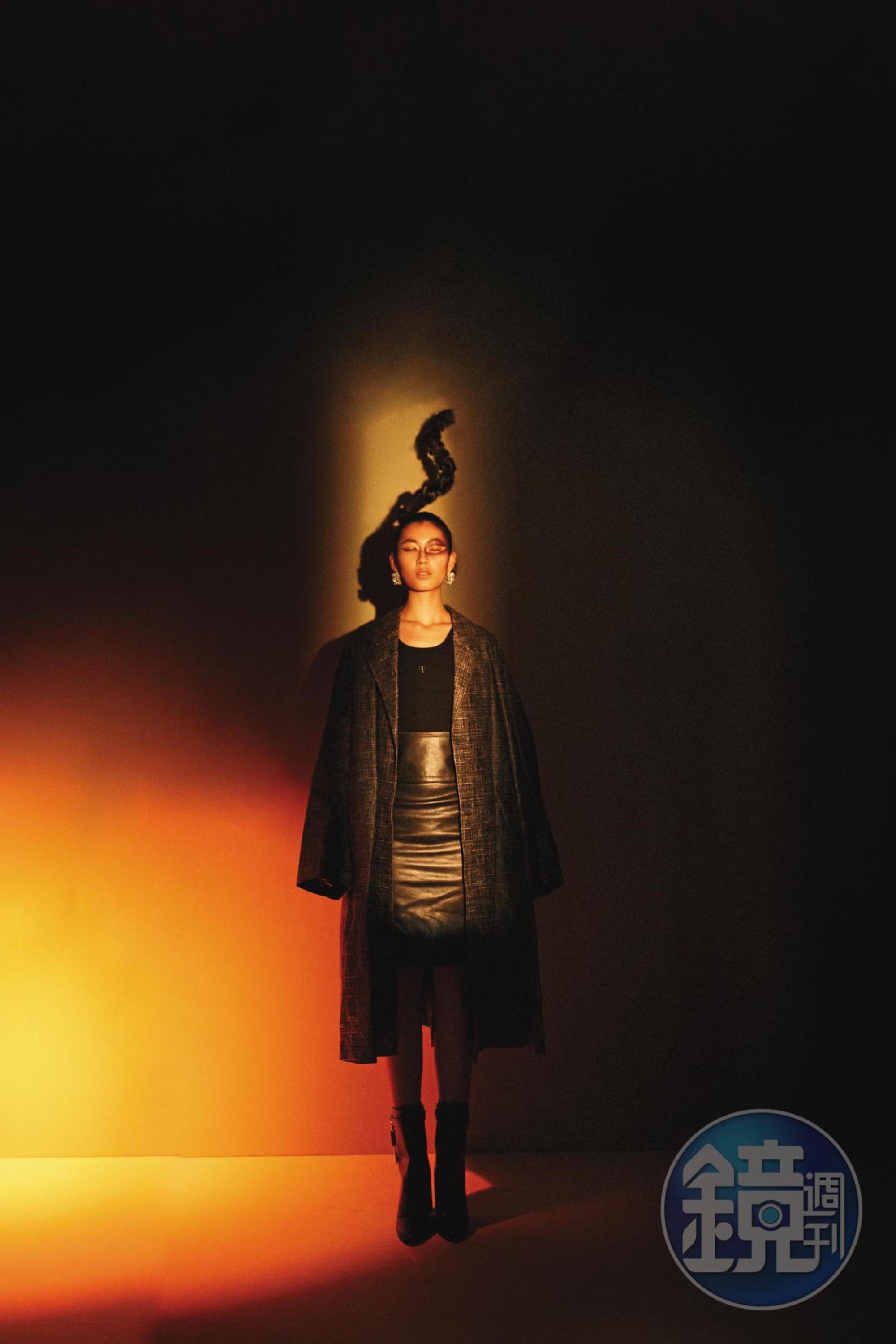 皮革印刷大衣,價格店洽,by BOTTEGA VENETA;黑色背心、皮革過膝裙、黑色膝下靴、銀色耳環,價格店洽,all by GIVENCHY。