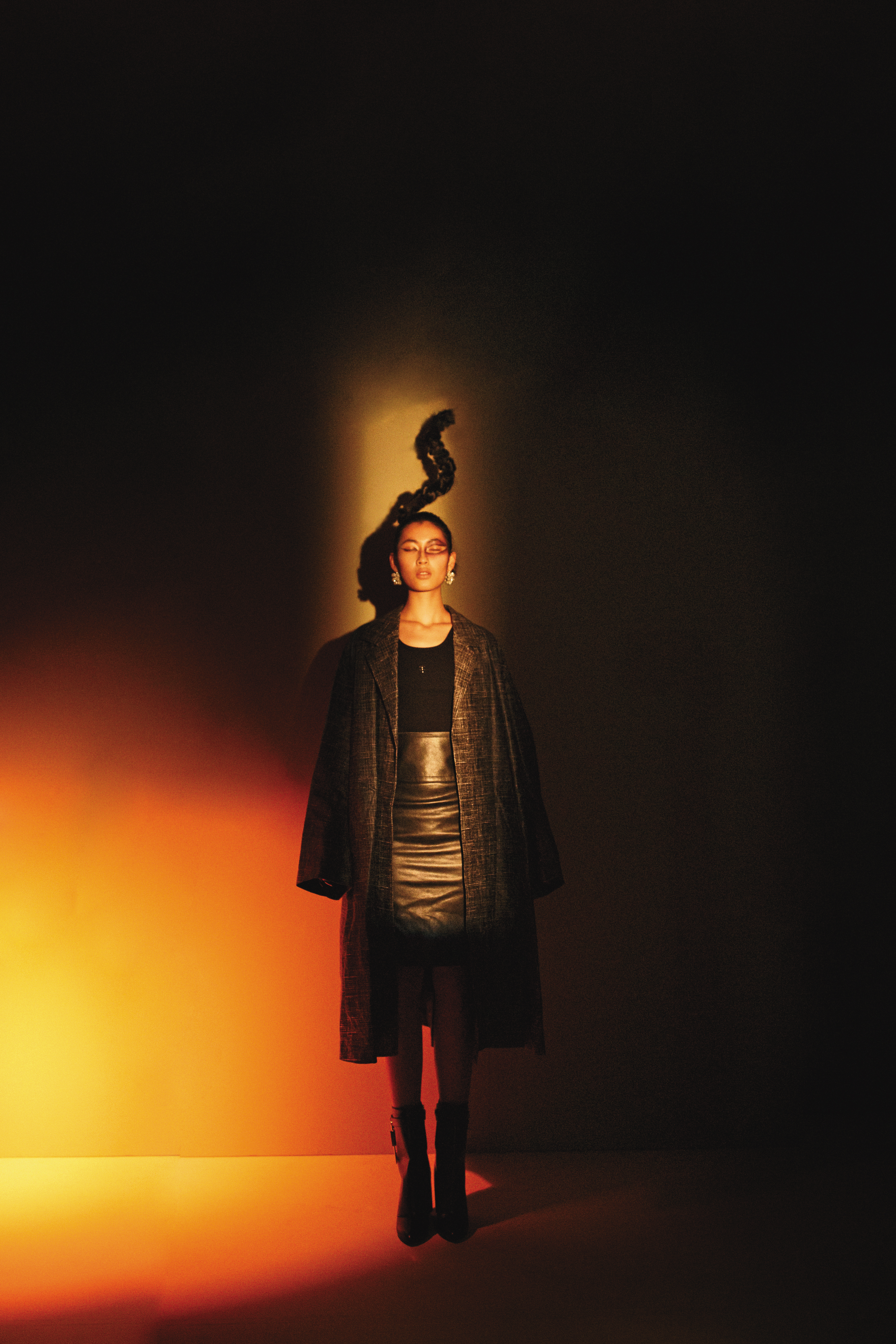 皮革印刷大衣，價格店洽，by BOTTEGA VENETA；黑色背心、皮革過膝裙、黑色膝下靴、銀色耳環，價格店洽，all by GIVENCHY。
