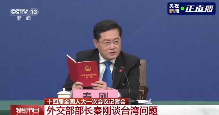 秦剛今在記者會上，拿出中國《憲法》翻閱，並引述起內容，「台灣是中華人民共和國的神聖領土的一部分。」（翻攝自央視）