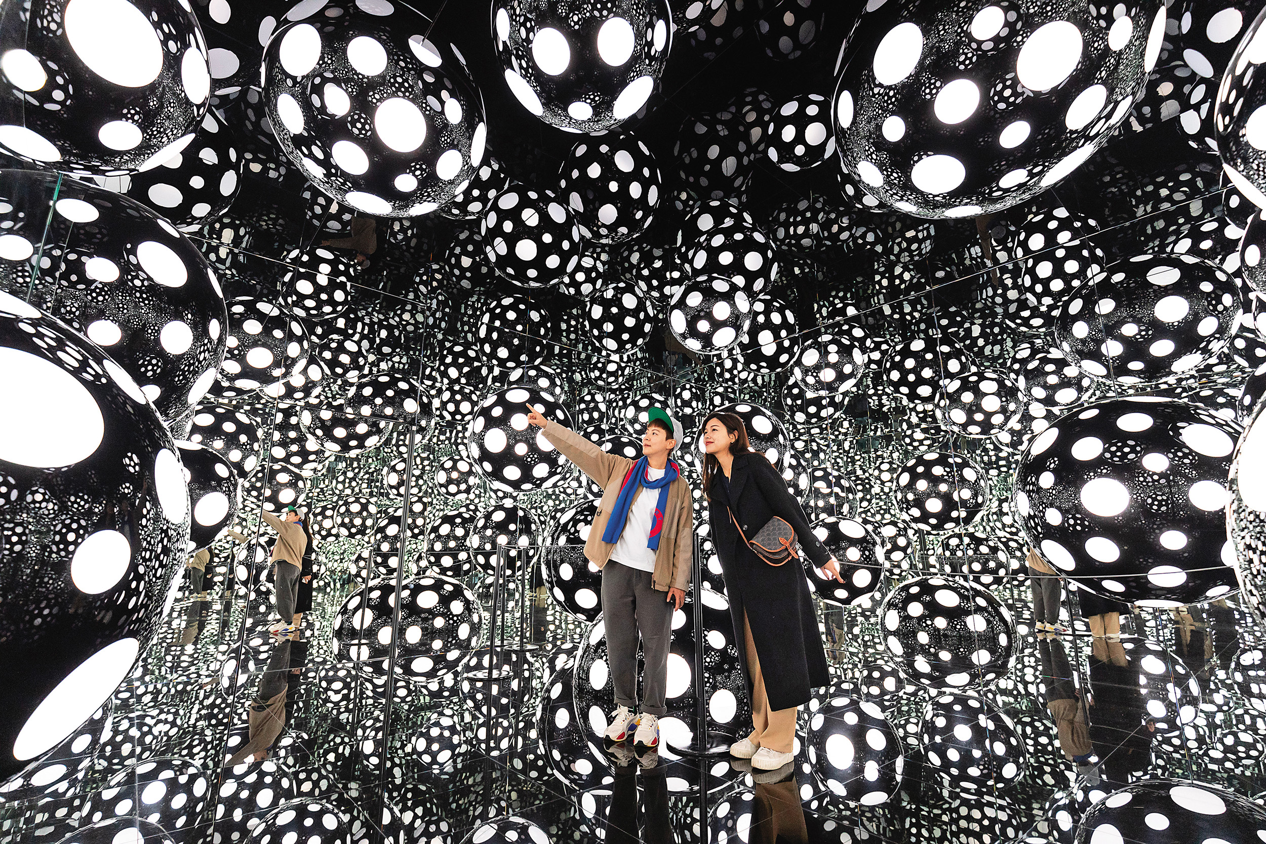 草間彌生為M+打造的全新作品《圓點執念——渴望天堂的愛》（2022），讓人宛如置身黑色圓點的萬花筒世界。