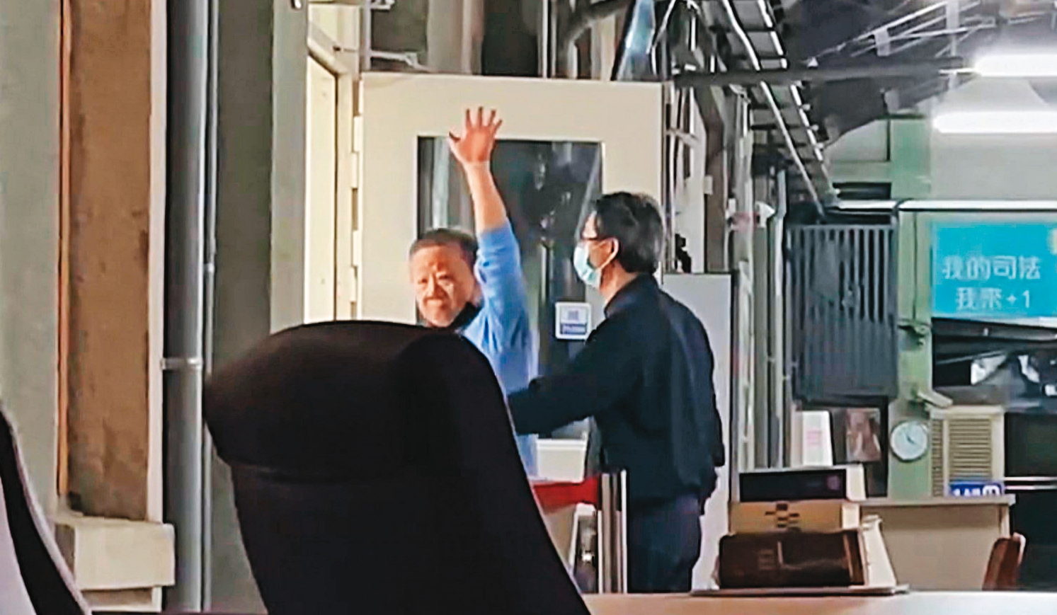 沈宗隆進入法庭審理前揮手對外示意,似乎展現對官司的信心,最後仍被法院裁押禁見。(翻攝《鏡新聞》)