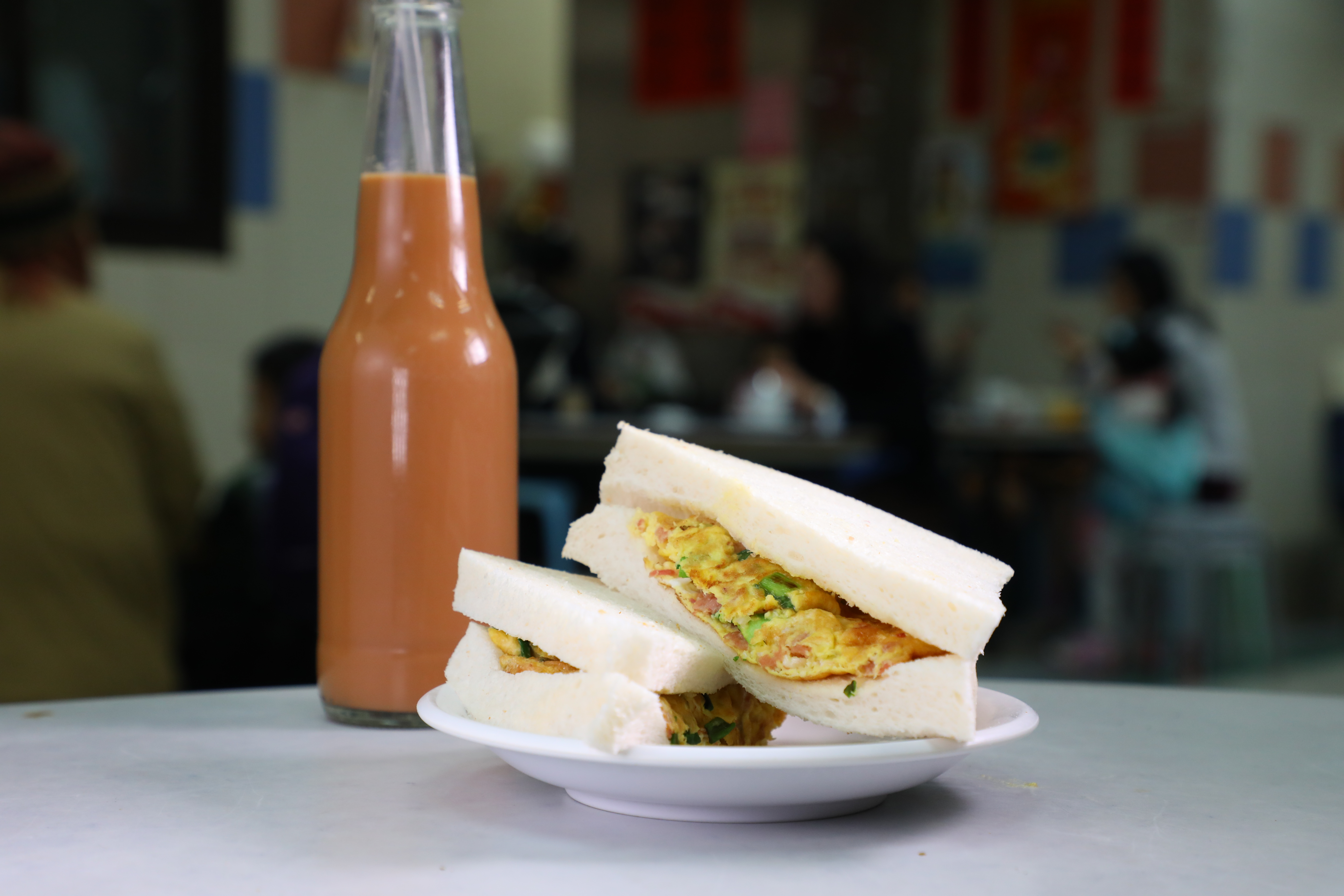 「瑞記咖啡」的「蛋牛治」（前，港幣20元／份）與懷舊感十足的「樽裝凍奶茶」（後，港幣18元／樽）。