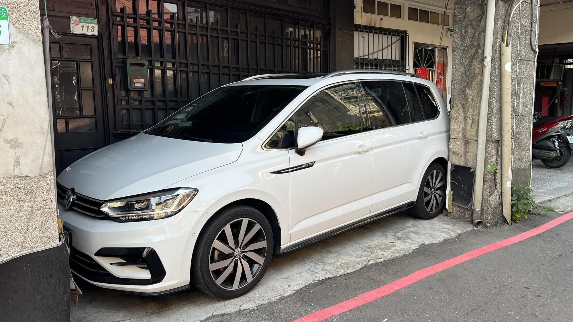 有網友曬出一輛白色轎車完美「卡」在騎樓柱子間，讓不少人都驚呆。（翻攝自路上觀察學院）