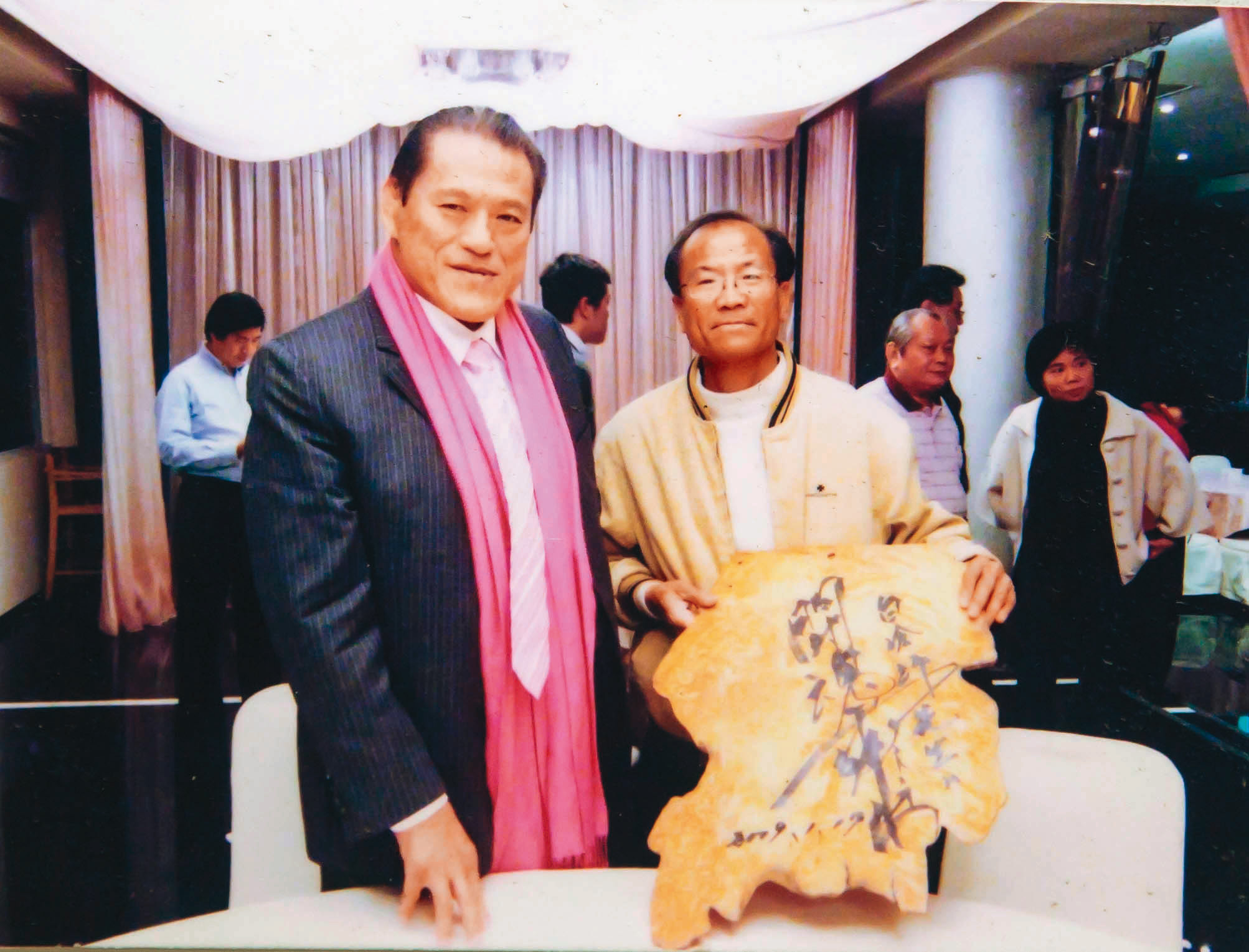 白滄沂（右）的作品常被政府機構用以贈送國際友人，日本摔角好手豬木（左）回贈親筆題字。（白滄沂提供）