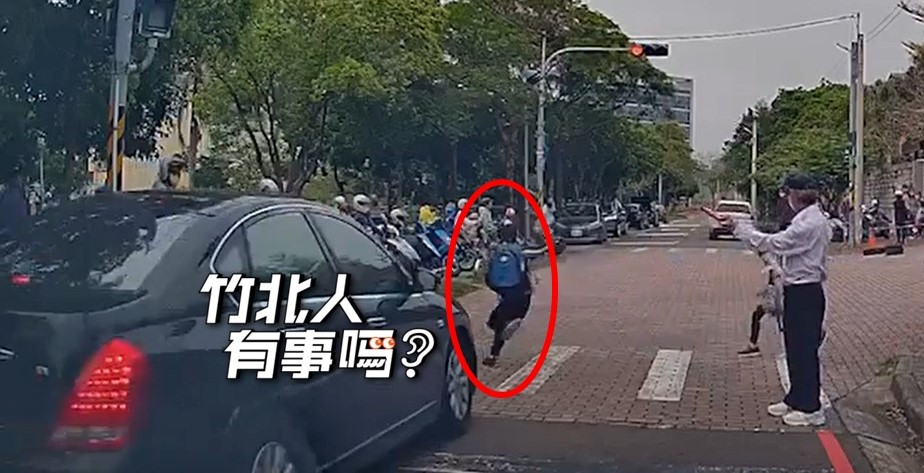 一輛黑色轎車經過校門前的斑馬線闖紅燈，差點撞上正在過馬路的小學生。（翻攝自竹北人有事嗎臉書社團）