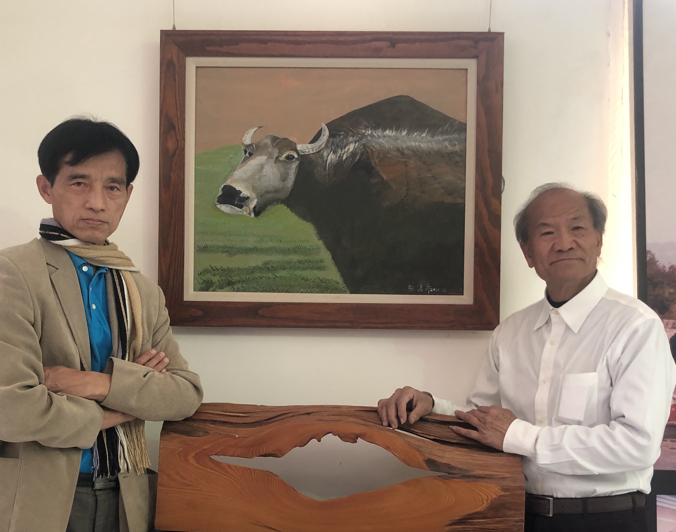 跨領域自學油畫的白滄沂(右)，正在中興新村開畫展，圖為畫家莊玉明（左）在白滄沂作品水牛前合影。（白滄沂提供）