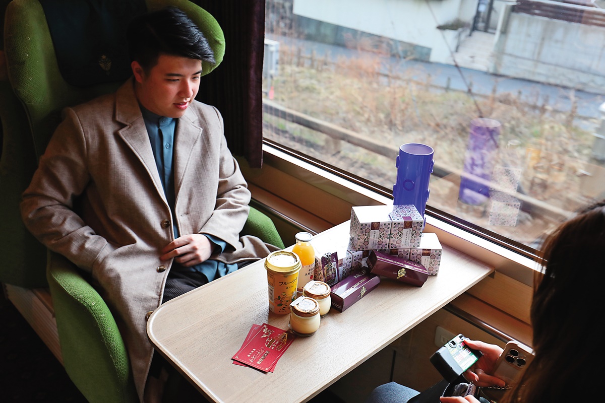 旅客開心地把剛採購的列車專屬紀念品和乘車證放在桌上拍照。