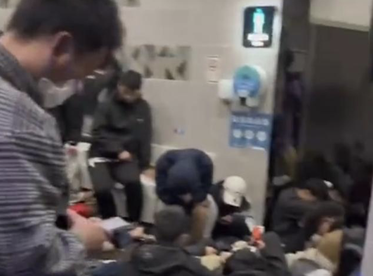 中國五一連假開始，有一群民眾因為沒訂到旅館，直接睡在公廁的走道。（翻攝自微博）