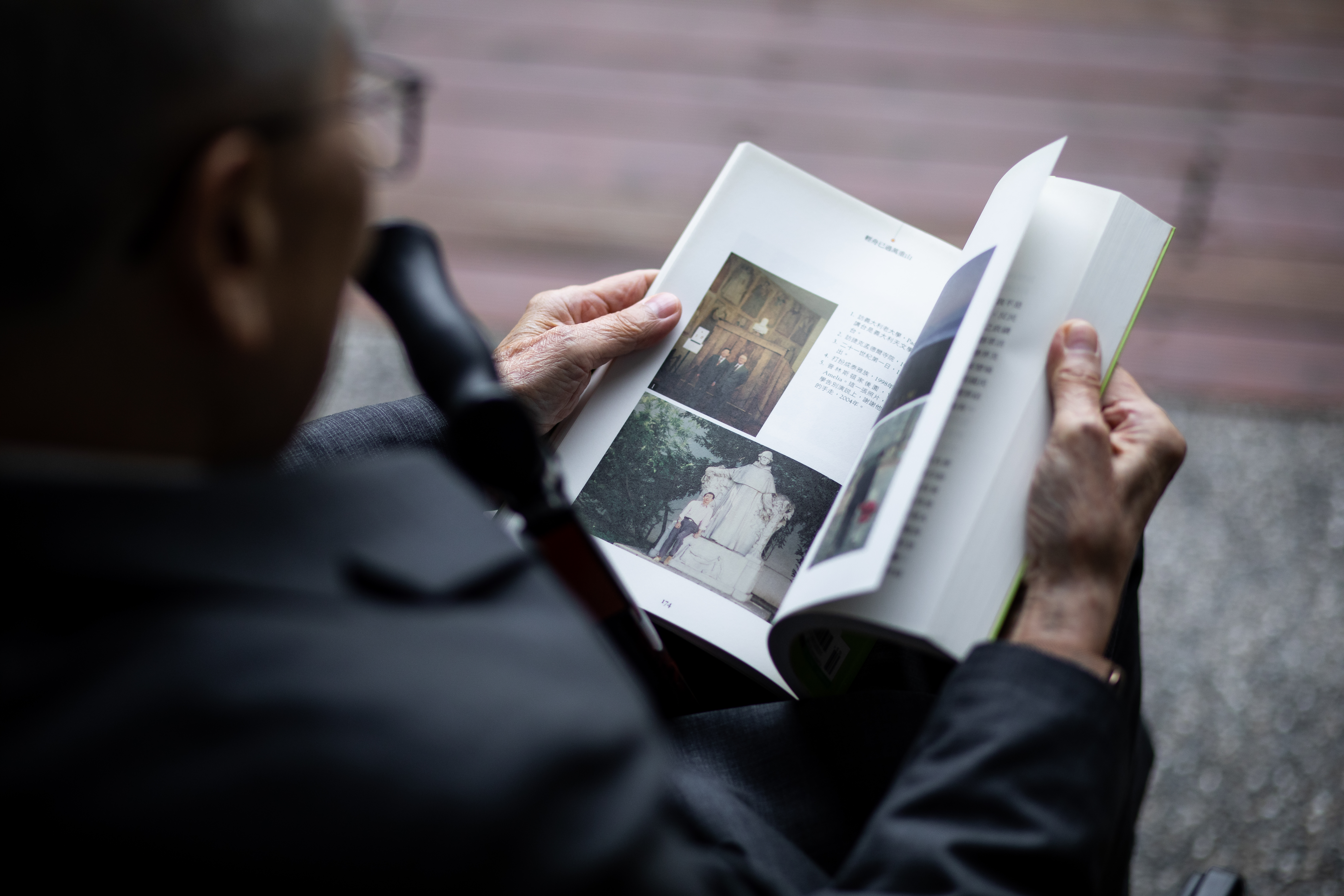 李明亮看自己寫的書，翻到照片頁時偶爾會陷入回憶，主動說起一張張照片的背後故事。