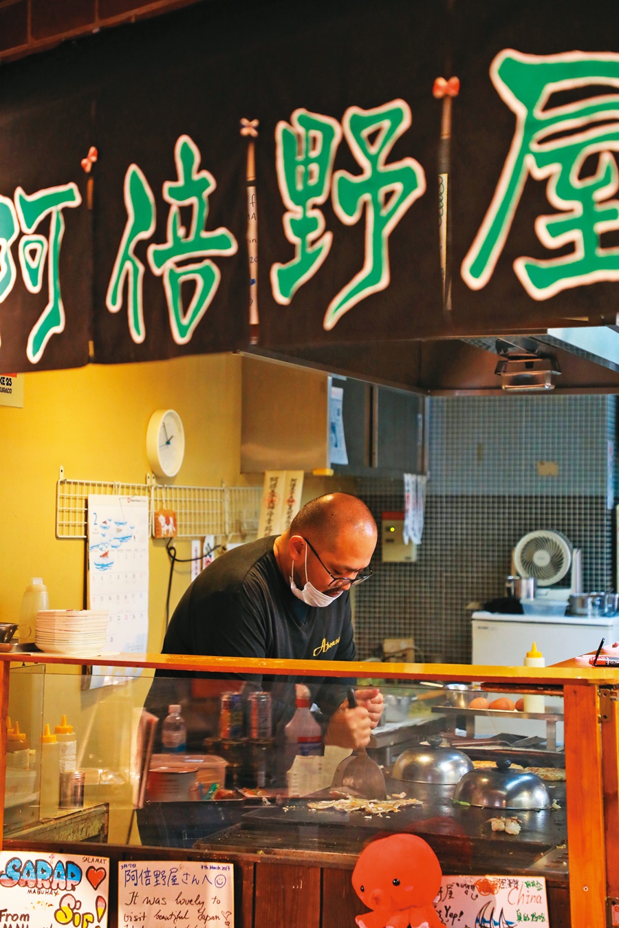 阿倍野屋的老闆認真在鐵板上製作各種煎餅。