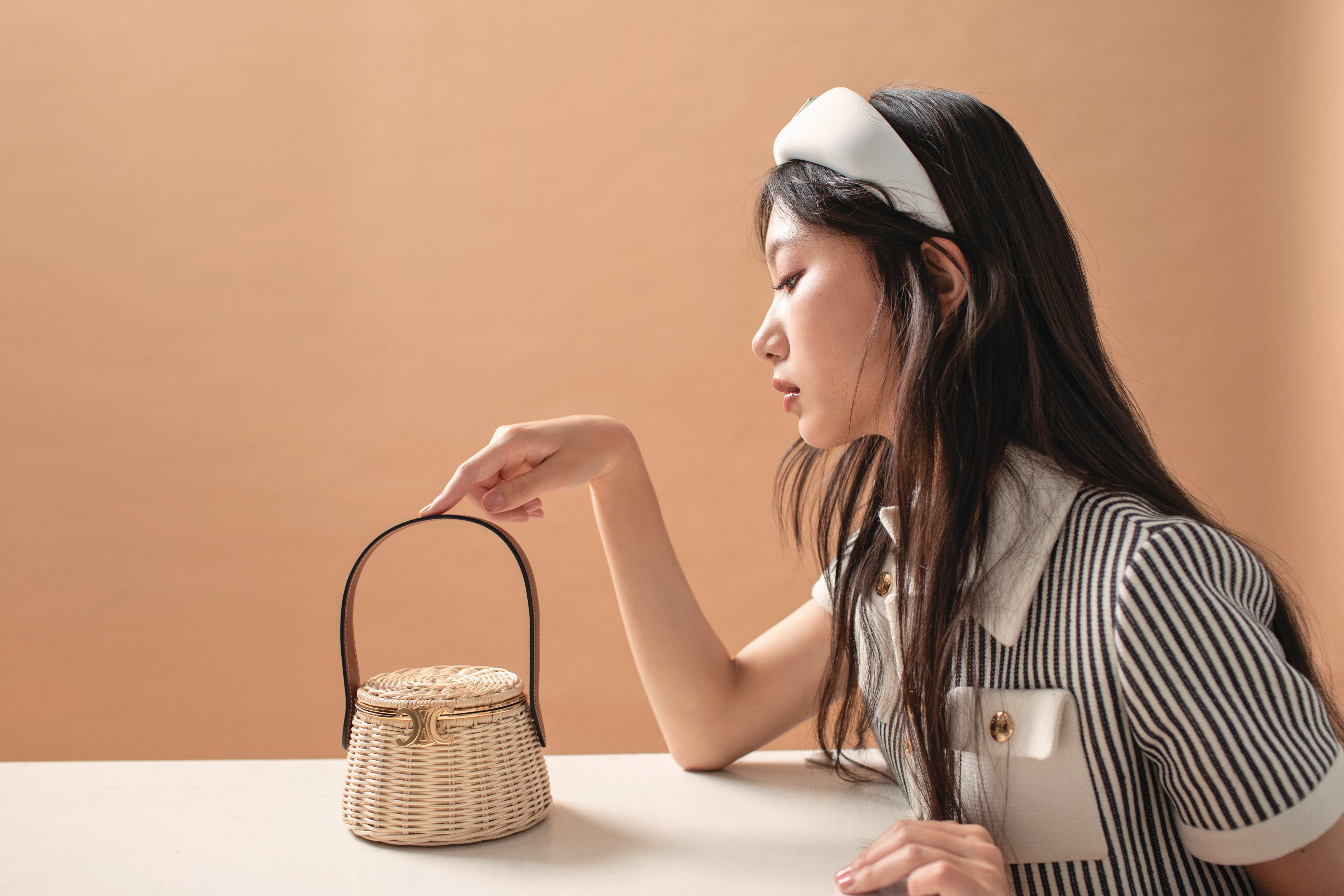 TRIOMPHE藤編手拿包 NT$135,000 by CELINE／海軍藍條紋CHELSEA外套 NT$120,000 by CELINE／再生尼龍頭帶 NT$17,000 by PRADA