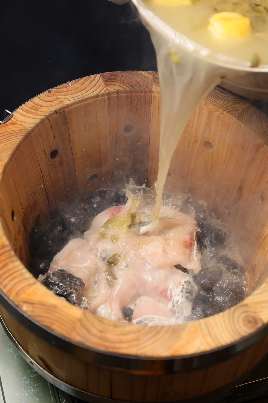 先將烏鱧魚片鋪上高溫石頭，再沖入酸菜高湯。