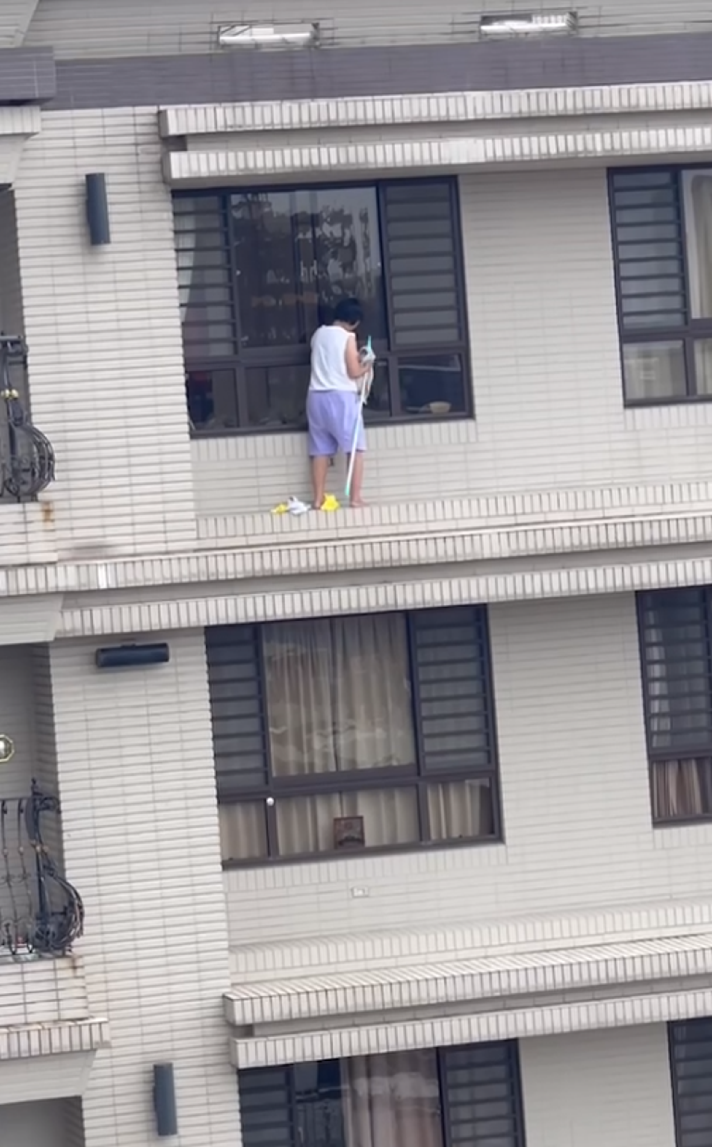 板橋一名婦人站在15樓高的窗外擦窗，讓對面住戶看了膽戰心驚。（截圖自爆廢公社）