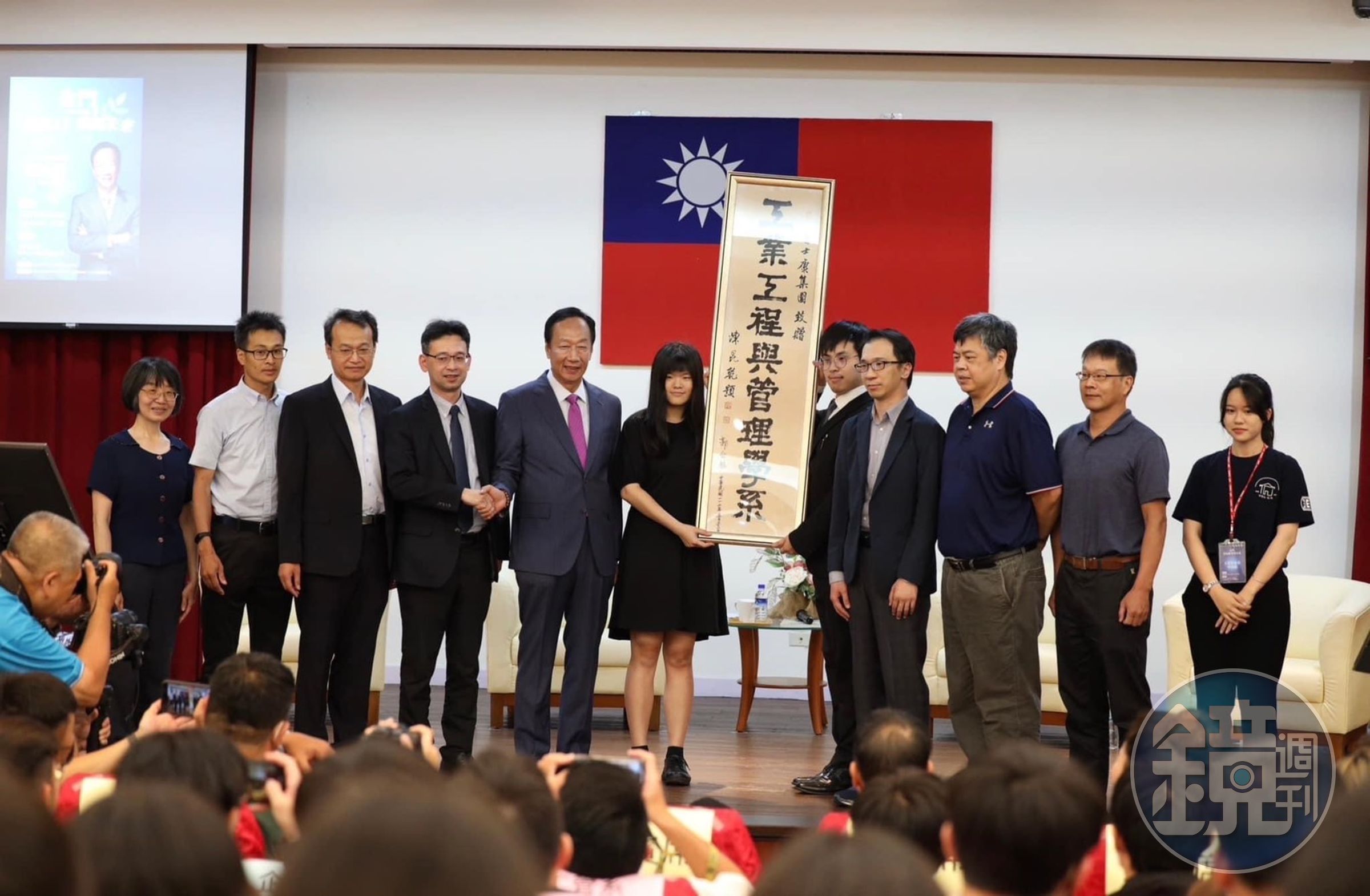 郭台銘(左5)受金門大學之邀前往演講,並在工管系牌匾上簽名留念。(讀者提供)