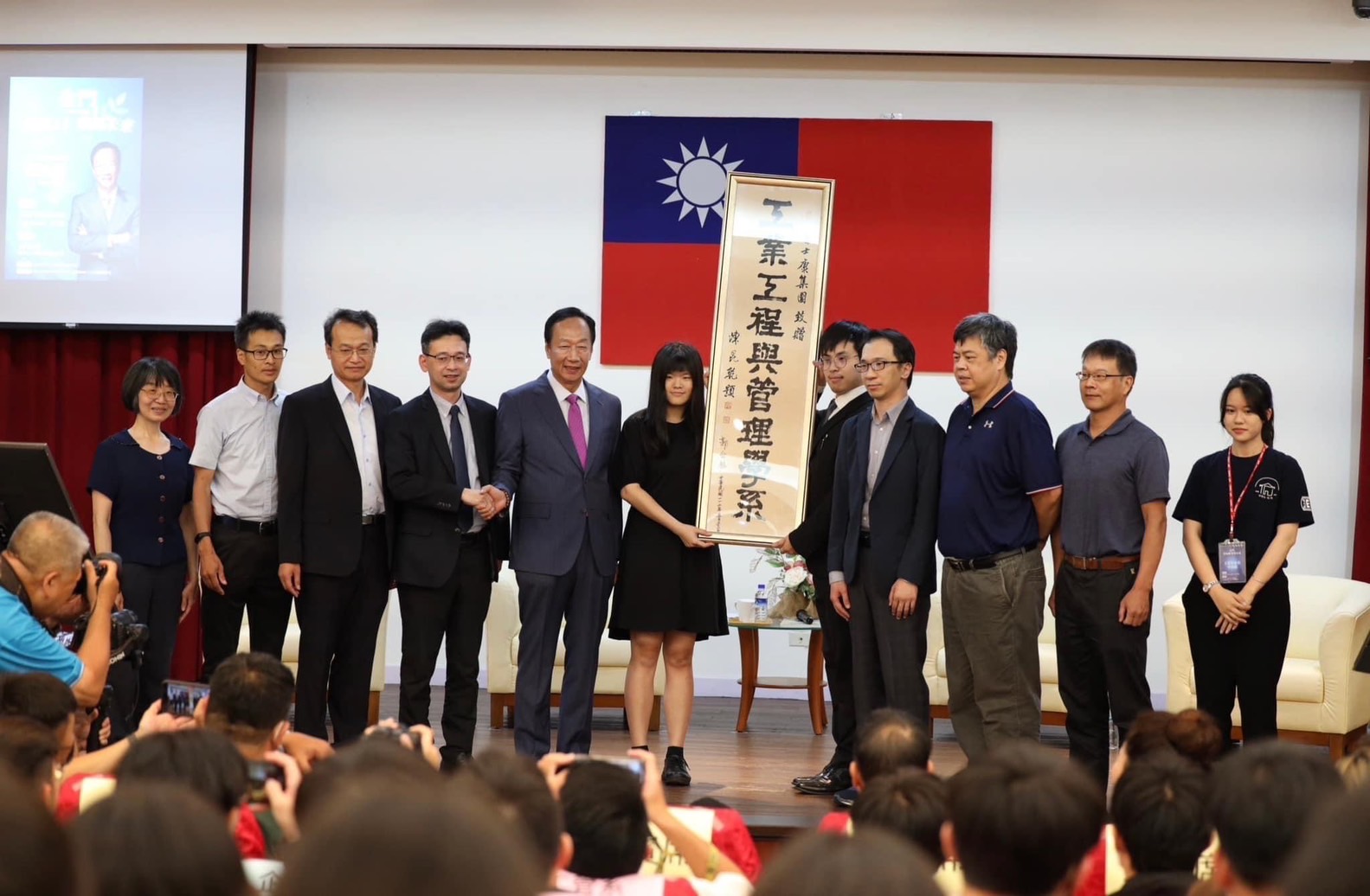 郭台銘(左5)受金門大學之邀前往演講,並在工管系牌匾上簽名留念。(讀者提供)