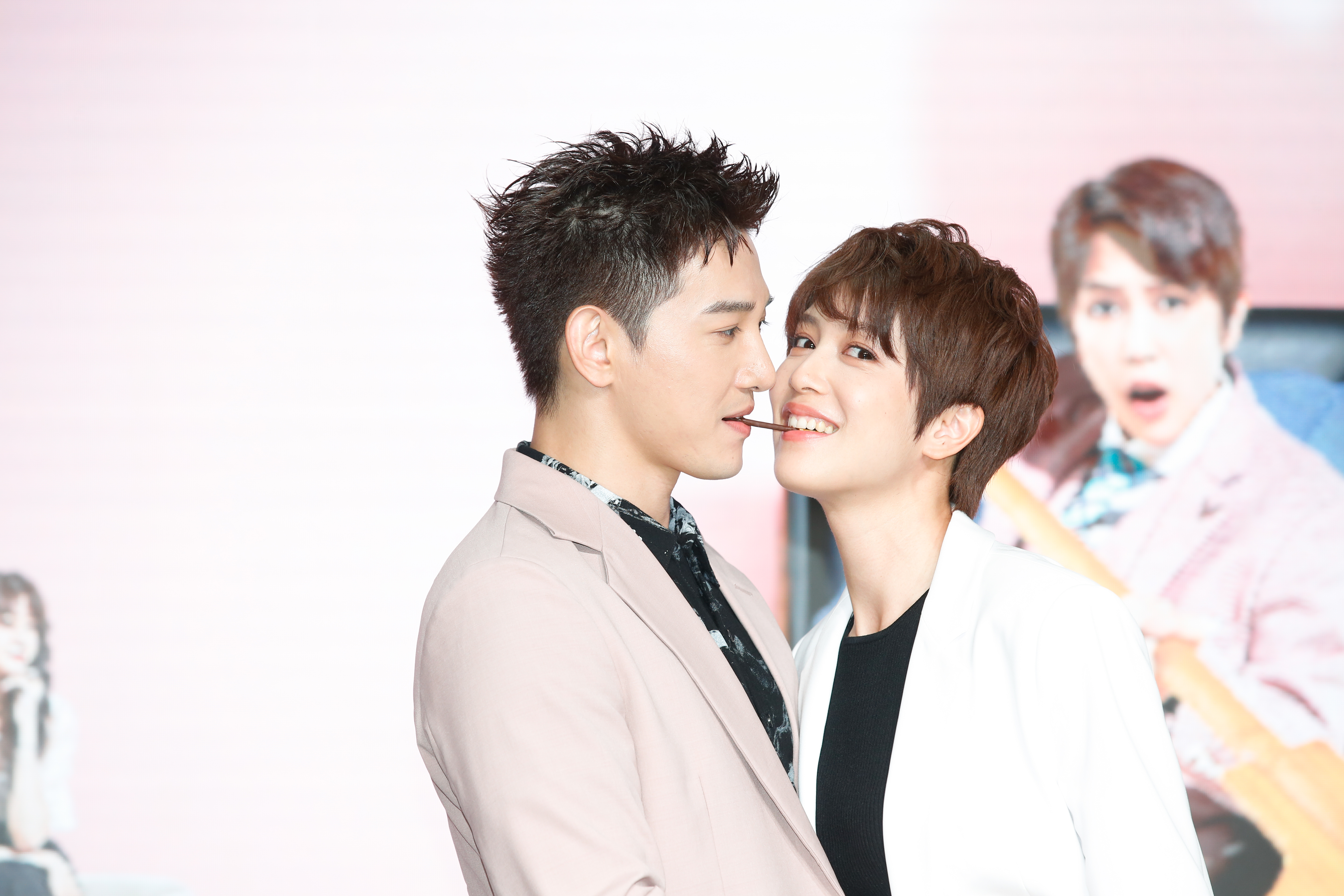 張立昂與劉奕兒以臉頰貼臉頰的方式互咬巧克力棒。