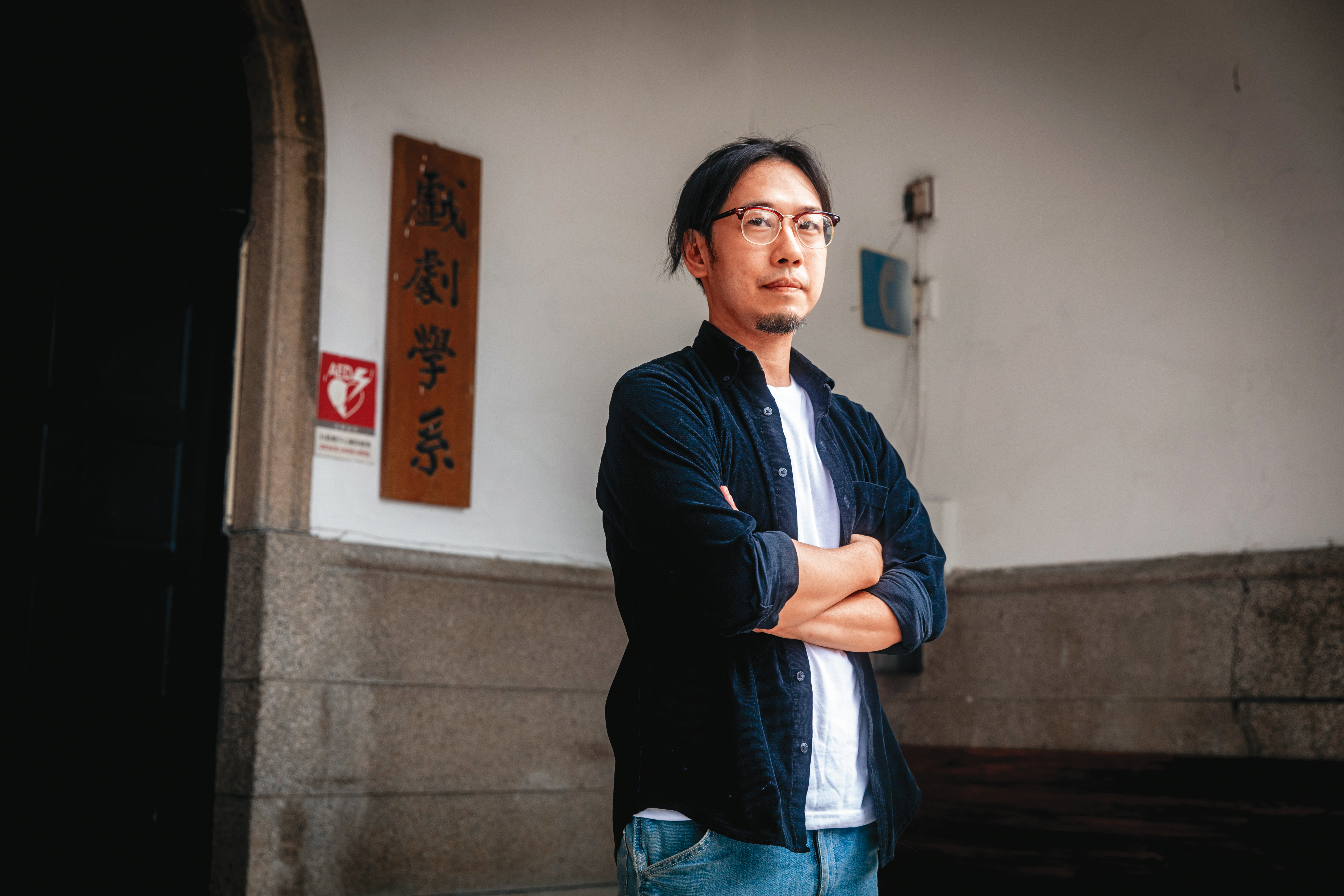 石巴朝回到台大戲劇系的大樓前拍照，隨後熟門熟路地帶我們到附近的旅館採訪。