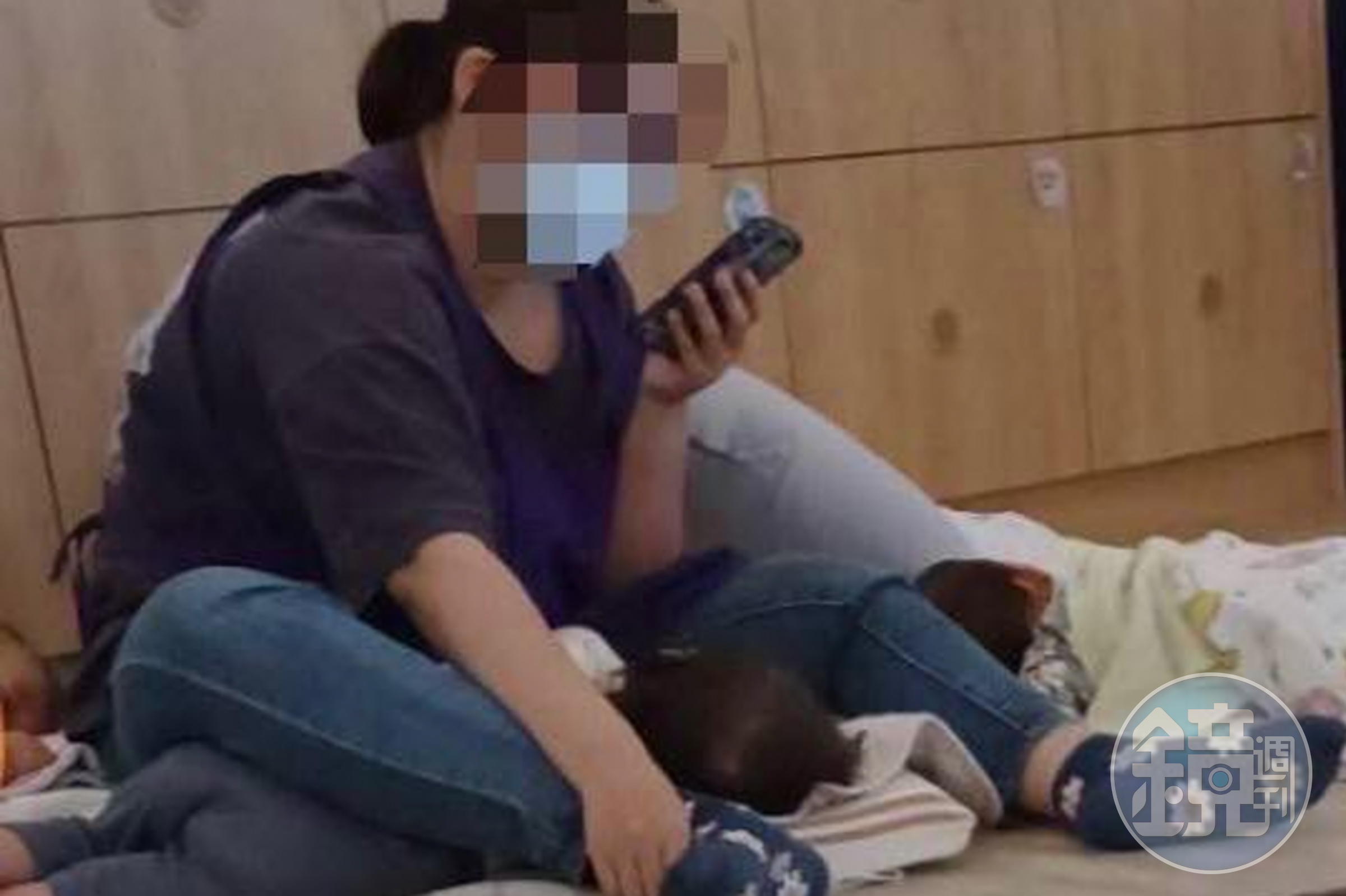幼保員被拍下邊看機邊用雙腿強行壓制幼童的畫面,引起公憤。(翻攝畫面)