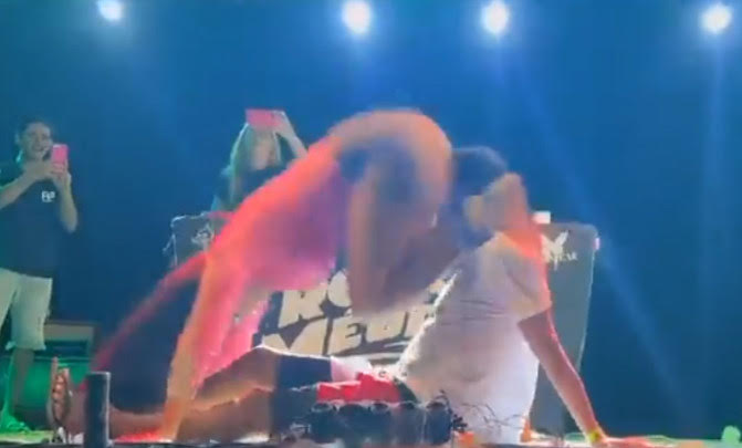 巴西一名女舞者跨坐觀眾身上，用下體撞擊男觀眾的臉，炒熱舞台氣氛。（翻攝推特@diretodomiolo）