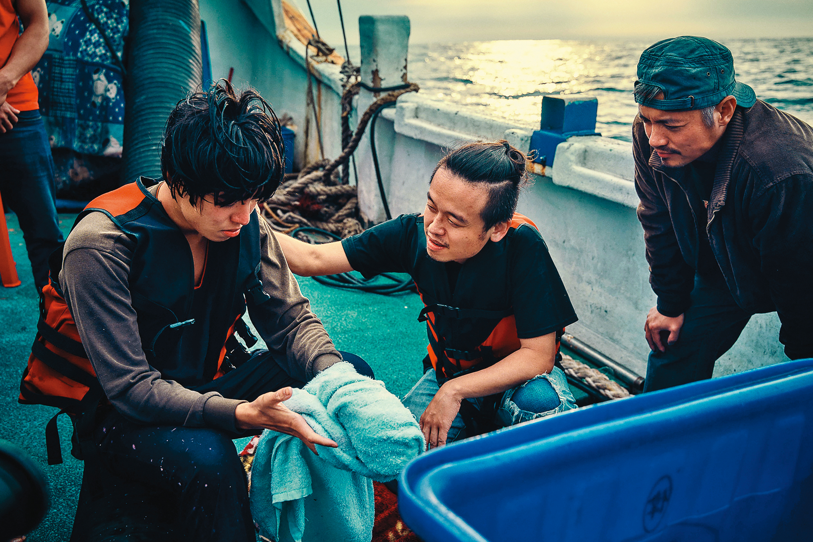 編導唐福睿(中)在漁船上與演員張耀(左)、范逸臣(右)討論。(鏡文學提供)