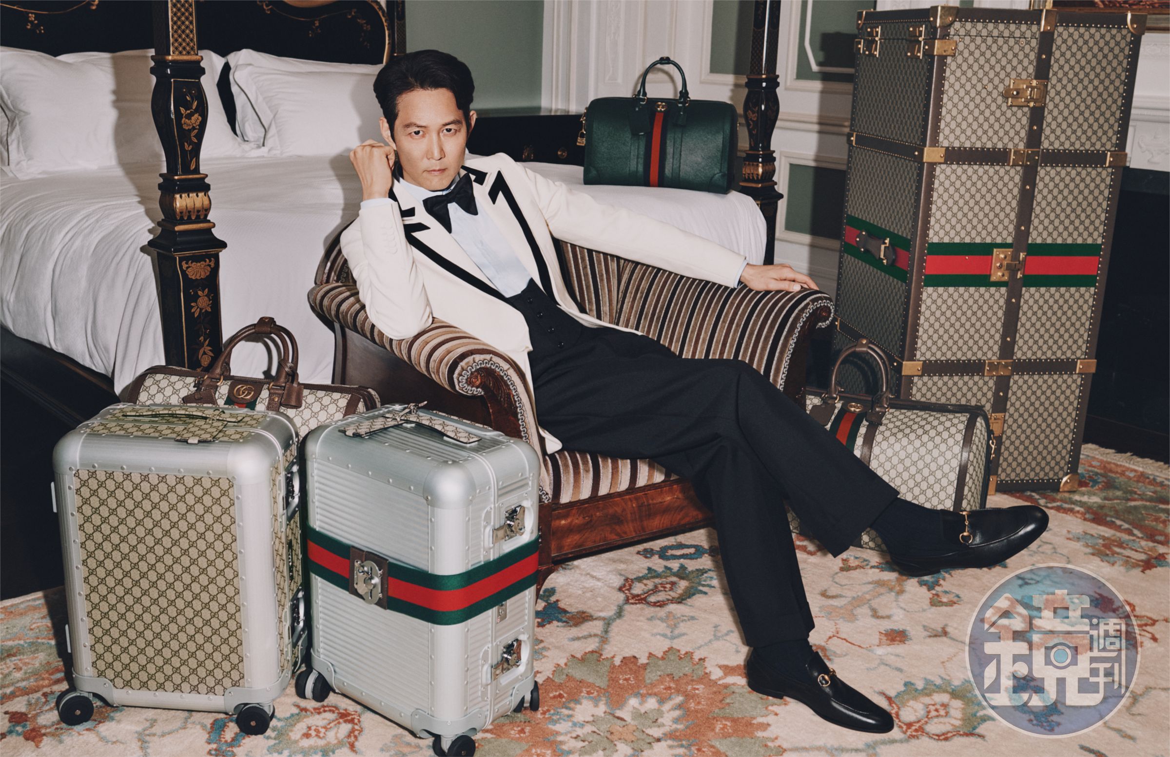 GUCCI旗艦皇家套房中使用GUCCI Décor系列傢俱，李政宰身旁則是GG字樣的全新GUCCI Porter系列、與米蘭FPM Milano共同創作，帶有Web圖樣裝飾的鋁合金行李箱、以及衣櫥行李箱。（古馳提供）