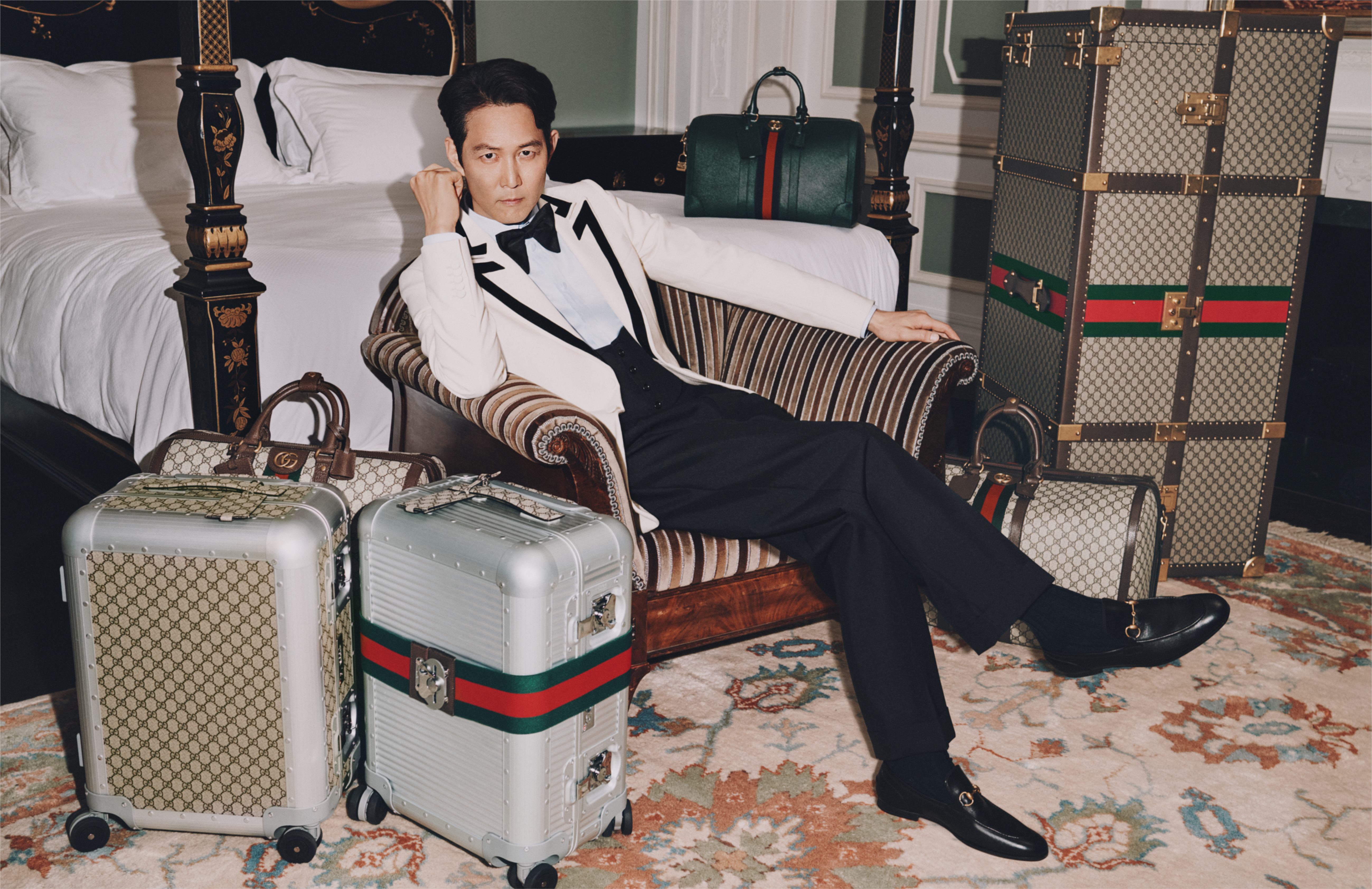 GUCCI旗艦皇家套房中使用GUCCI Décor系列傢俱,李政宰身旁則是GG字樣的全新GUCCI Porter系列、與米蘭FPM Milano共同創作,帶有Web圖樣裝飾的鋁合金行李箱、以及衣櫥行李箱。(古馳提供)