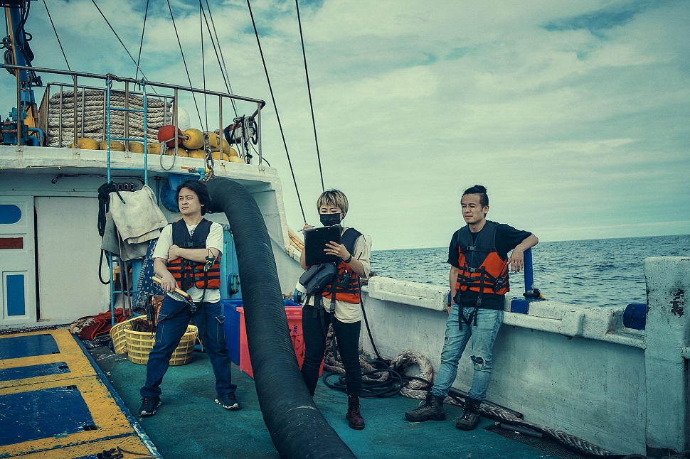編導唐福睿（右）與工作人員在漁船上準備拍攝。（鏡文學提供）
