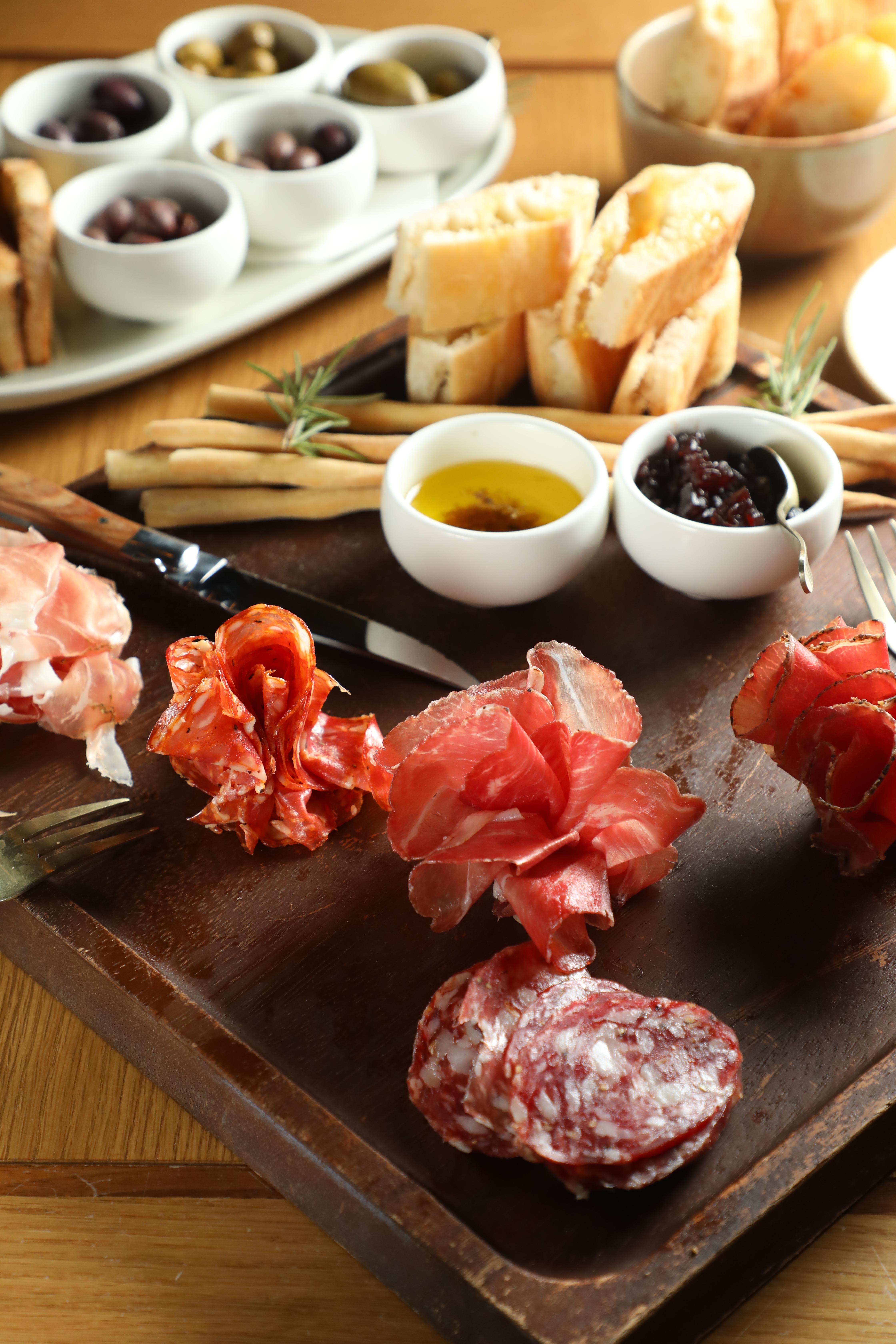 綜合熟肉盤「PUOPOLO ARTISAN SALUMI」（前，）鹹香美味，集滿5種橄欖的「PARAFIELD OLIVES」（後，）也很涮嘴。