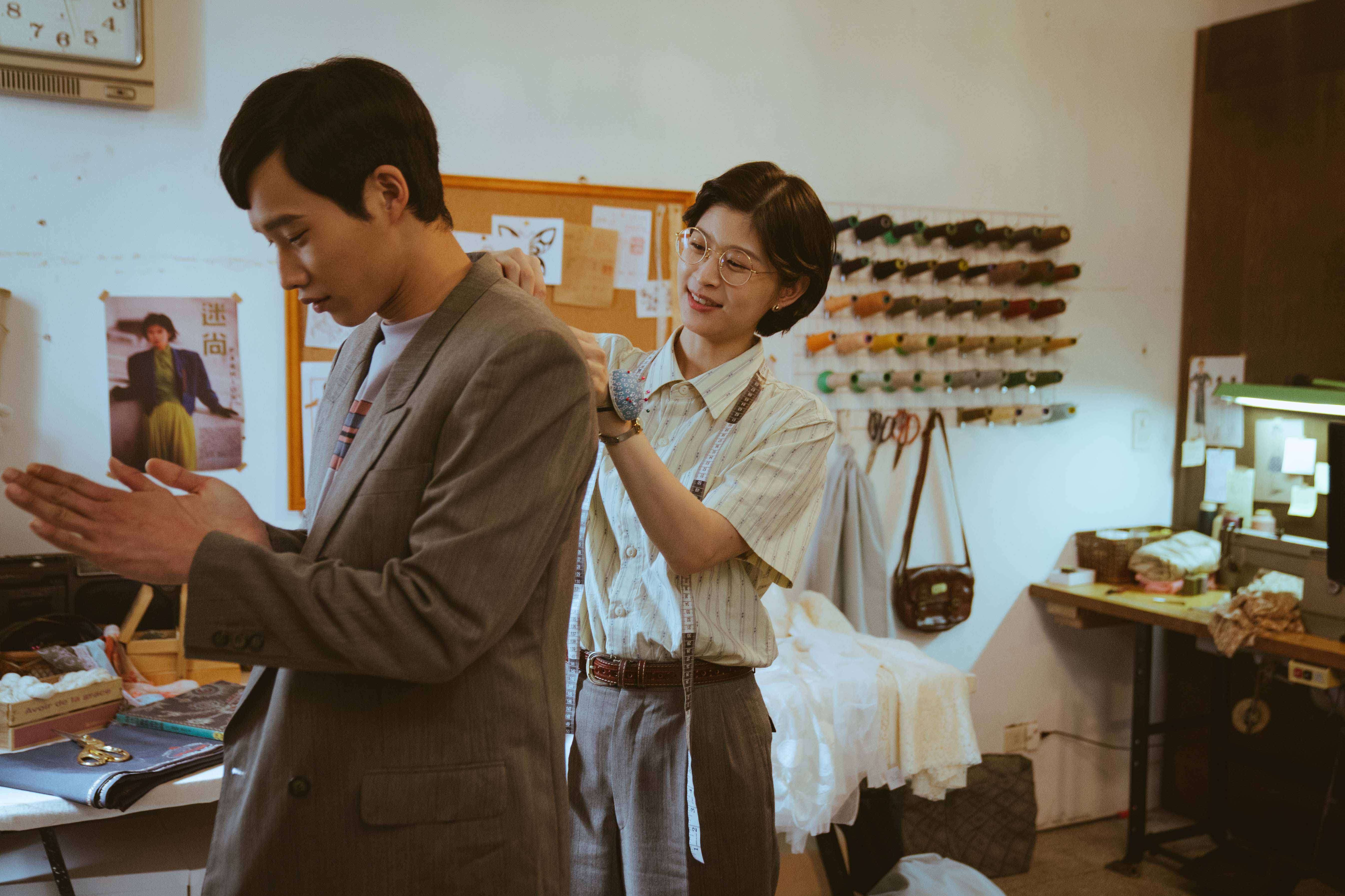 江宜蓉(右)替黃冠智量身打造結婚西裝,花絮中出現的辦桌菜「紅蟳米糕」,則是黃冠智擔心江宜蓉忙於製衣,特別做給好友的美味心意。(紅衣小女孩股份有限公司提供)