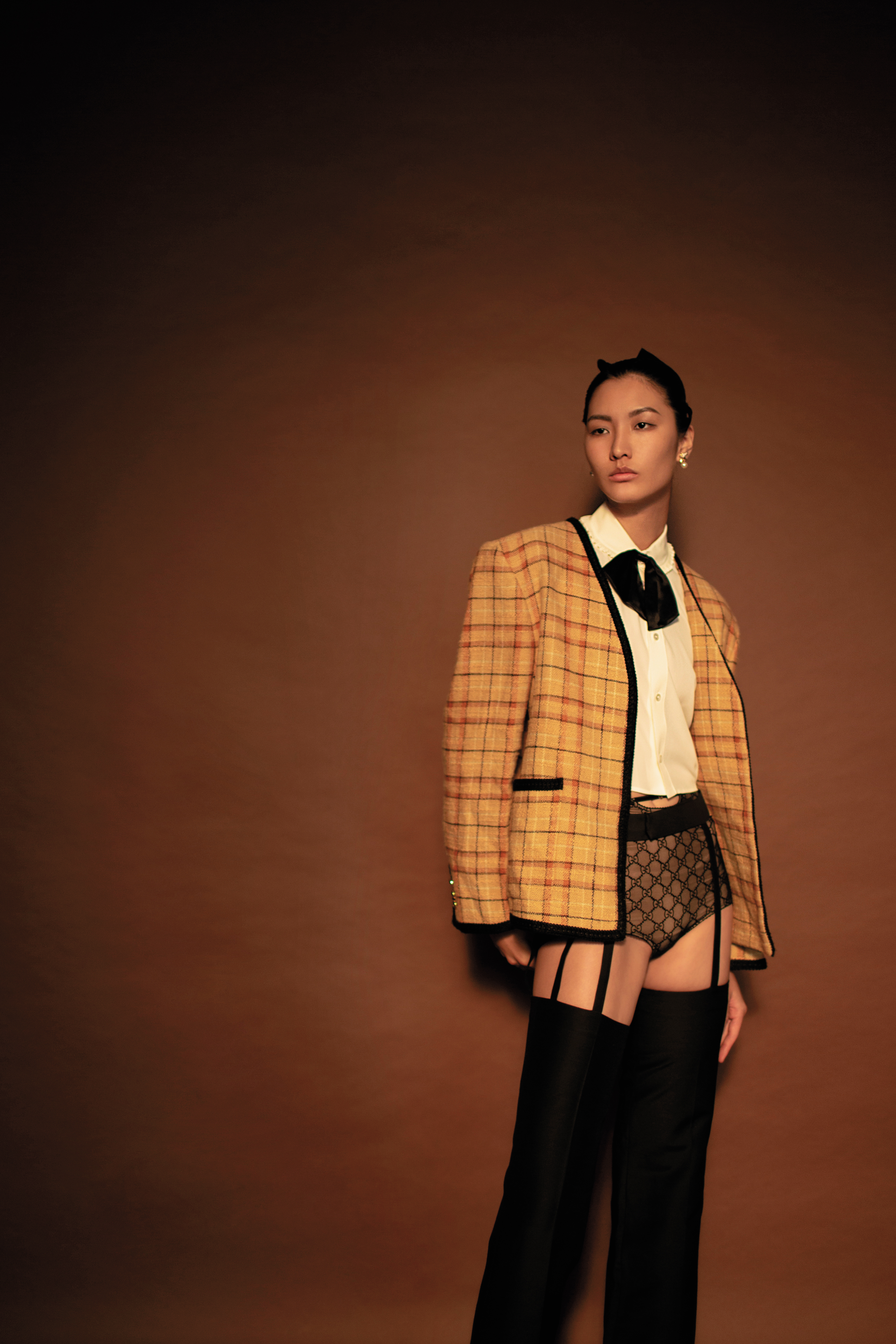 橙色格紋單排釦夾克 NT$112,300 by GUCCI；蝴蝶結飾領襯衫 NT$63,000 by CELINE BY HEDI SLIMANE；黑色真絲剪裁長褲 NT$64,200 by GUCCI；星星造型珍珠耳環 NT$15,500 by FERRAGAMO。