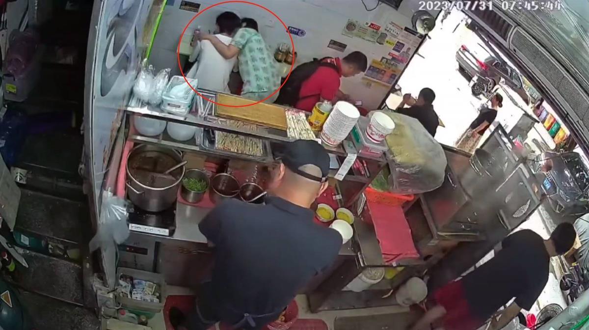 身穿白衣的男子在早餐店角落用餐，卻遭一名陌生女子強吻。（翻攝自極目新聞）