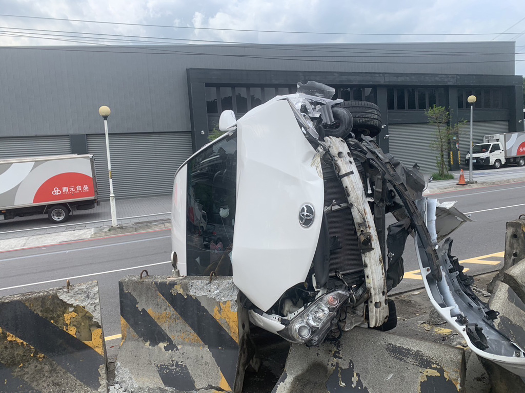 白色休旅車自撞分隔島後翻覆，肇事者酒駕落跑。（翻攝畫面）