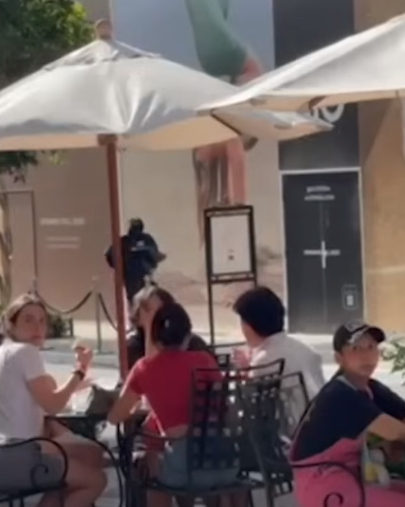 身穿黑衣的男子手上抱著精品從店內快步跑出，廣場中甚至還有一般民眾坐著。（翻攝自 KTLA 5 YouTube頻道）