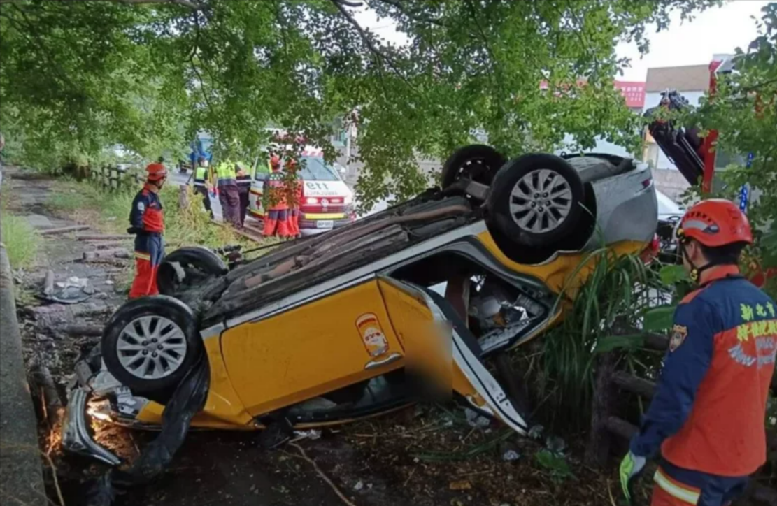 陳姓駕駛開計程車載客，不慎打滑導致自撞路邊護欄後翻覆。（翻攝畫面）